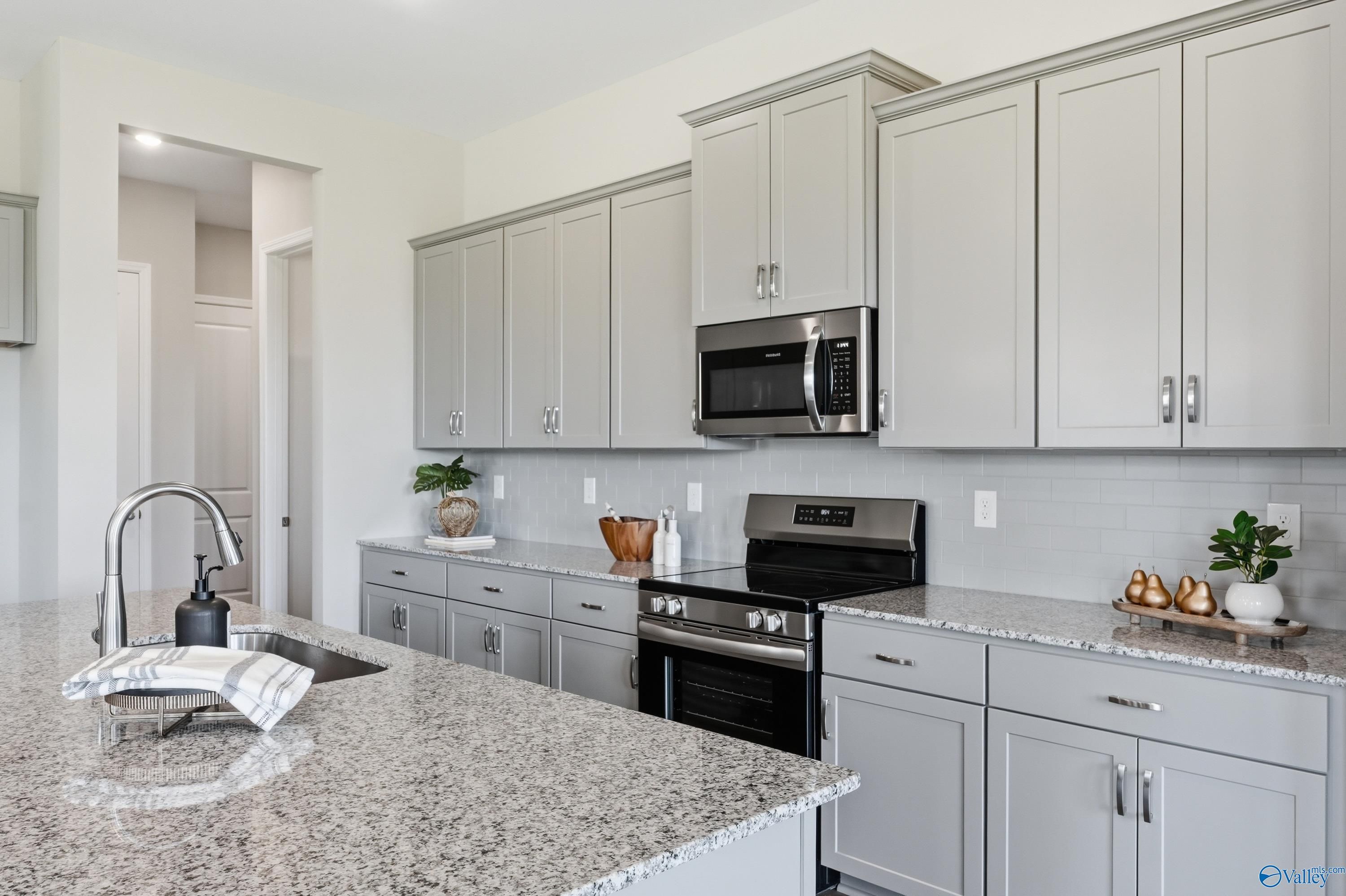 Modern kitchen featuring gray shaker cabinets, granite countertops, stainless steel appliances in Davidson Homes The Arcadia B, Huntsville