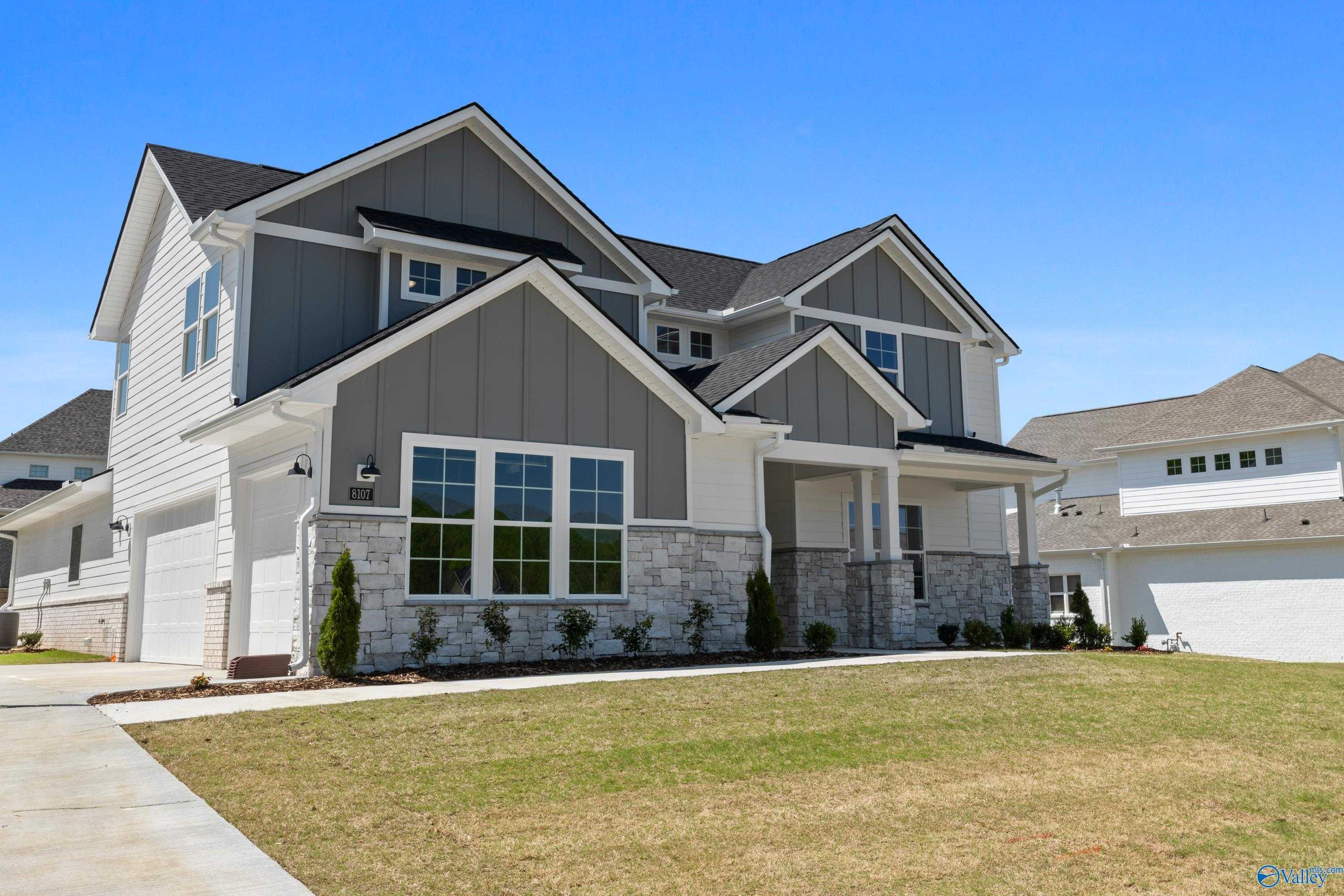 Modern two-story 5-bedroom home with gray shiplap siding, stone accents, and 3-car garage in The Meadows at Hampton Cove, Owens Cross Roads, Alabama