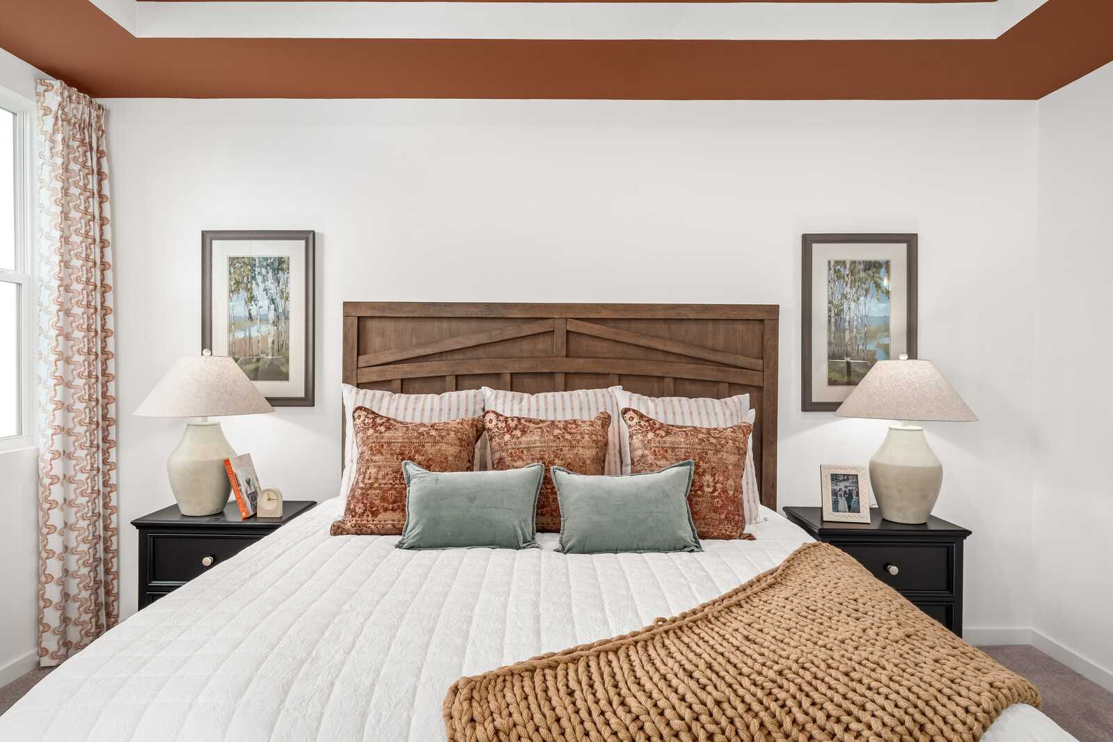 Cozy bedroom at Calista Farms White House TN by Davidson Homes with wooden headboard, terracotta pillows, knit throw