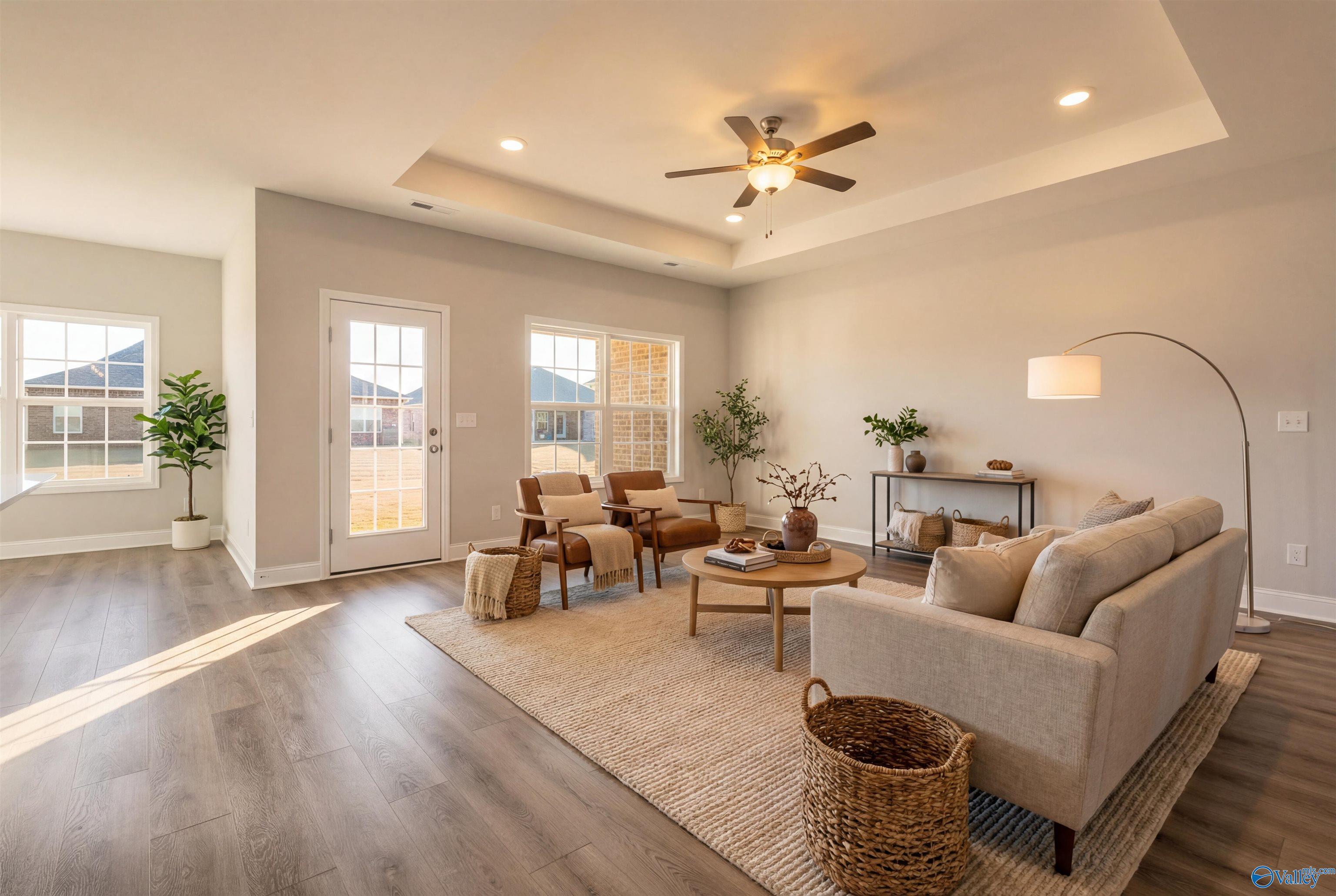 Cozy living room with beige sofa, armchairs, French doors to backyard, ceiling fan in Davidson Homes The Montgomery B, Toney, Alabama