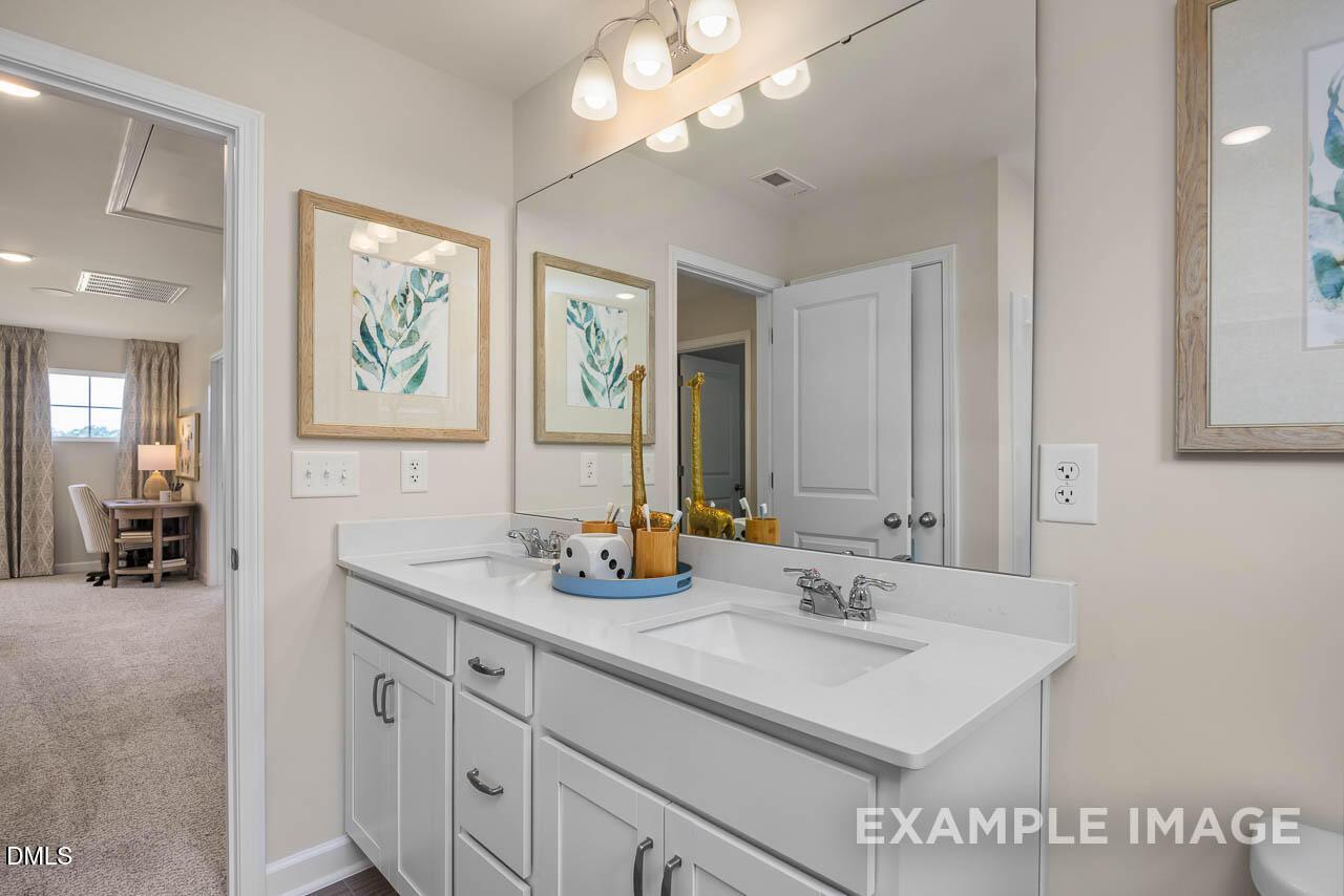 Modern double vanity with white cabinets, dual sinks, and leaf artwork in master bath of The Willow B by Davidson Homes, Wake Forest, NC