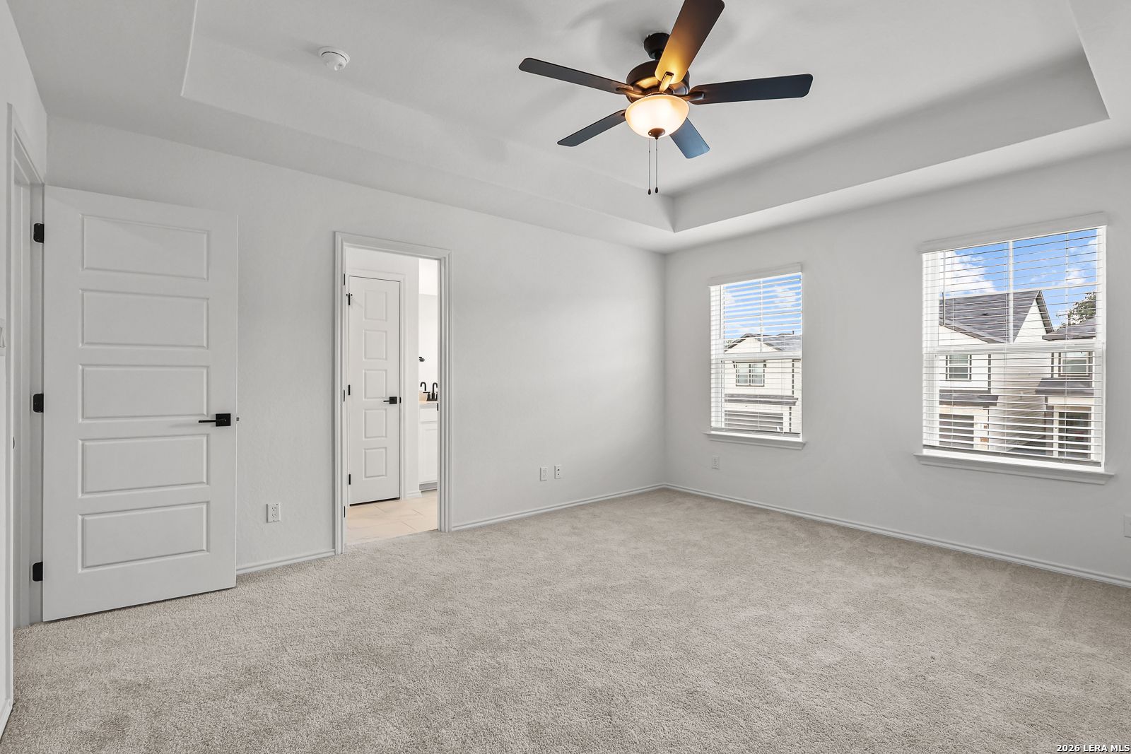 Spacious bedroom with tray ceiling and ceiling fan in The Gillian C floor plan at Meadows at Oak Creek, San Antonio, Texas.