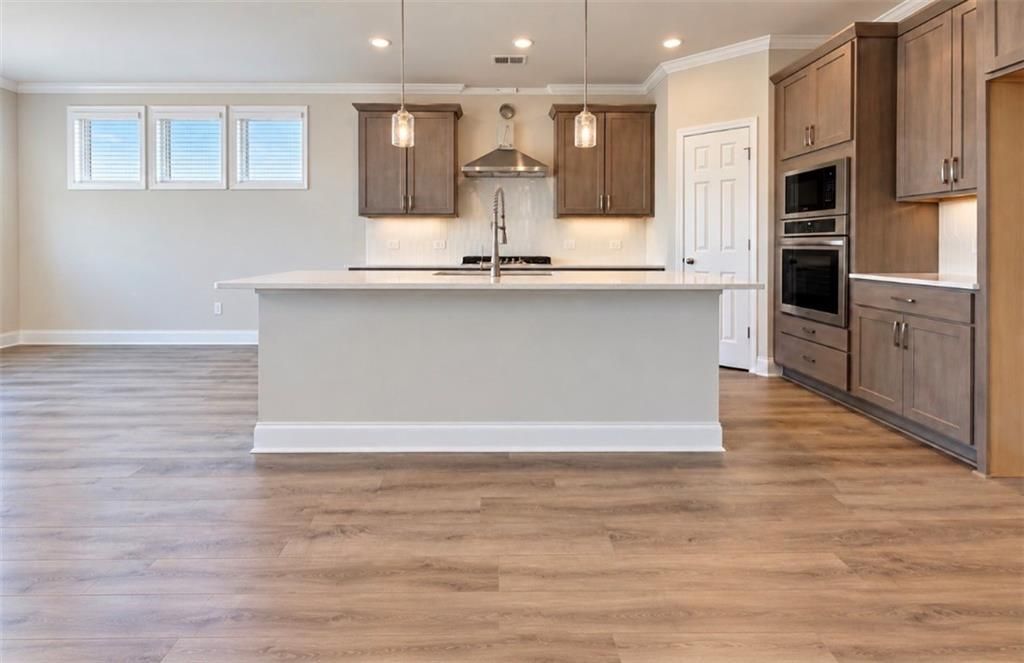 Modern kitchen with large island, pendant lights, and stainless appliances in Davidson Homes Harrison H plan, Hoschton, GA