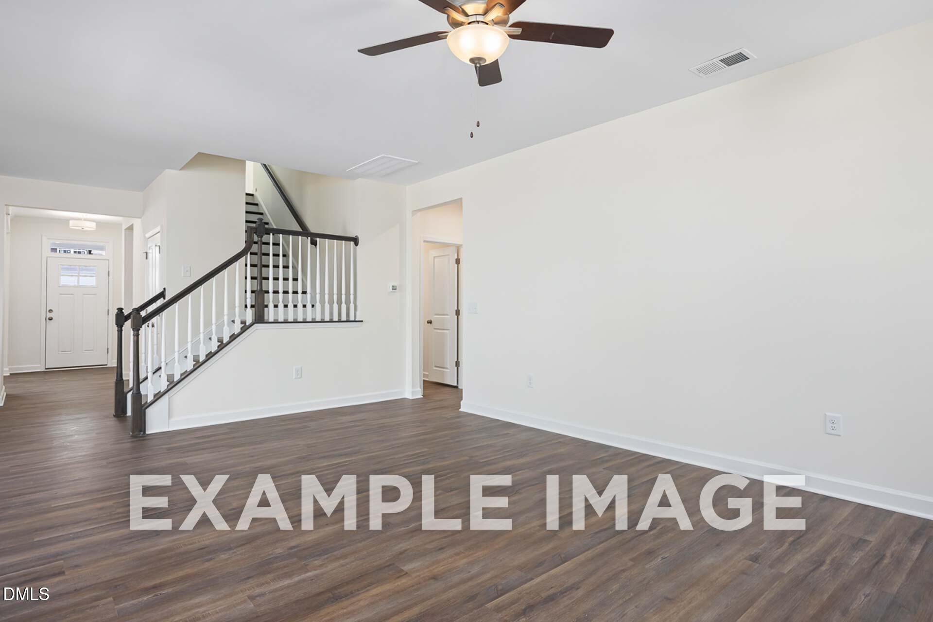 Elegant two-story foyer with wooden staircase, ceiling fan, and hardwood floors in Davidson Homes The Ash B, Zebulon, NC