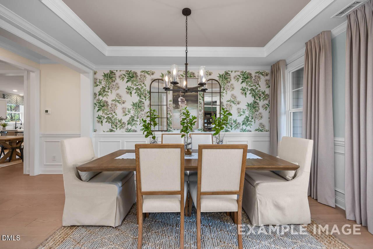Elegant dining room with floral wallpaper, rectangular wooden table, beige chairs and chandelier in The Crawford D by Davidson Homes, Angier, NC