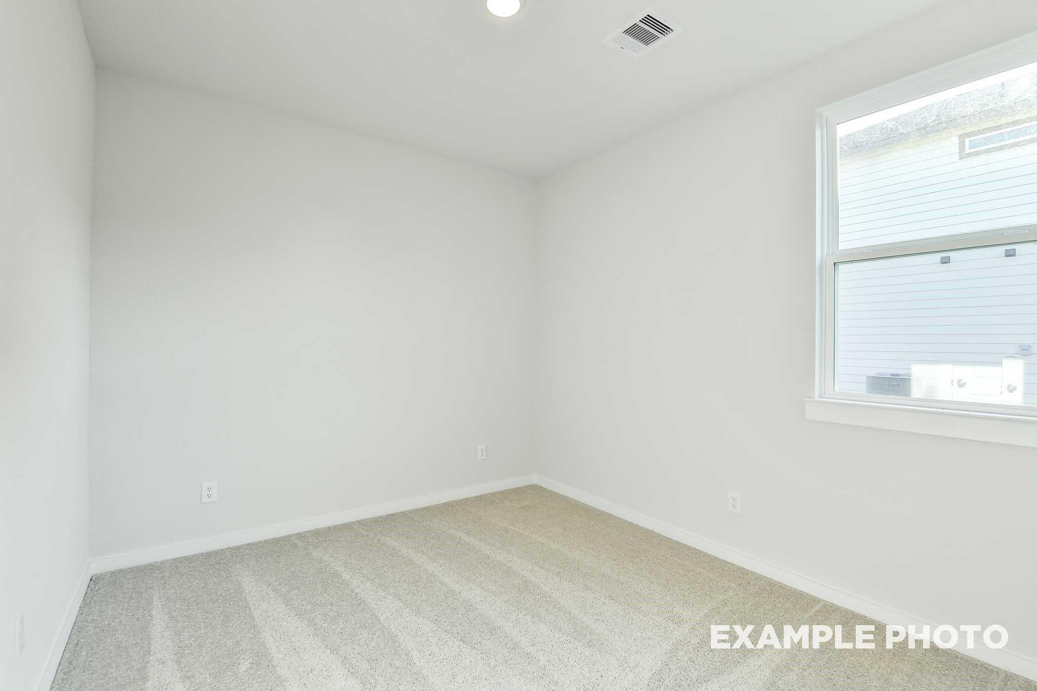 Bright empty bedroom with beige carpet, white walls, and window in Davidson Homes The Colorado G, Conroe, Texas
