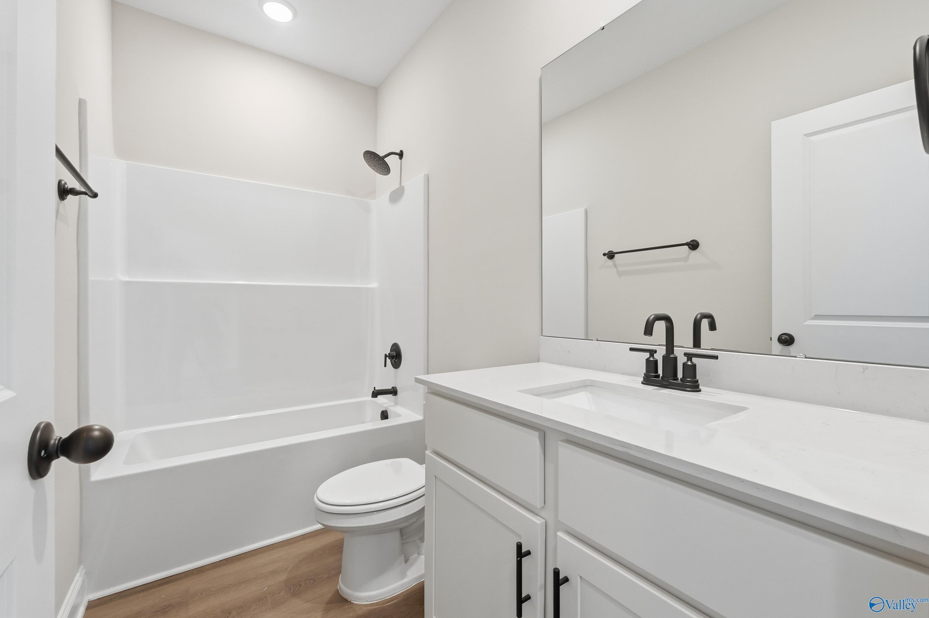 Bright guest bathroom with white tub-shower combo, vanity, and toilet in Davidson Homes The Franklin E, Hazel Green, Alabama