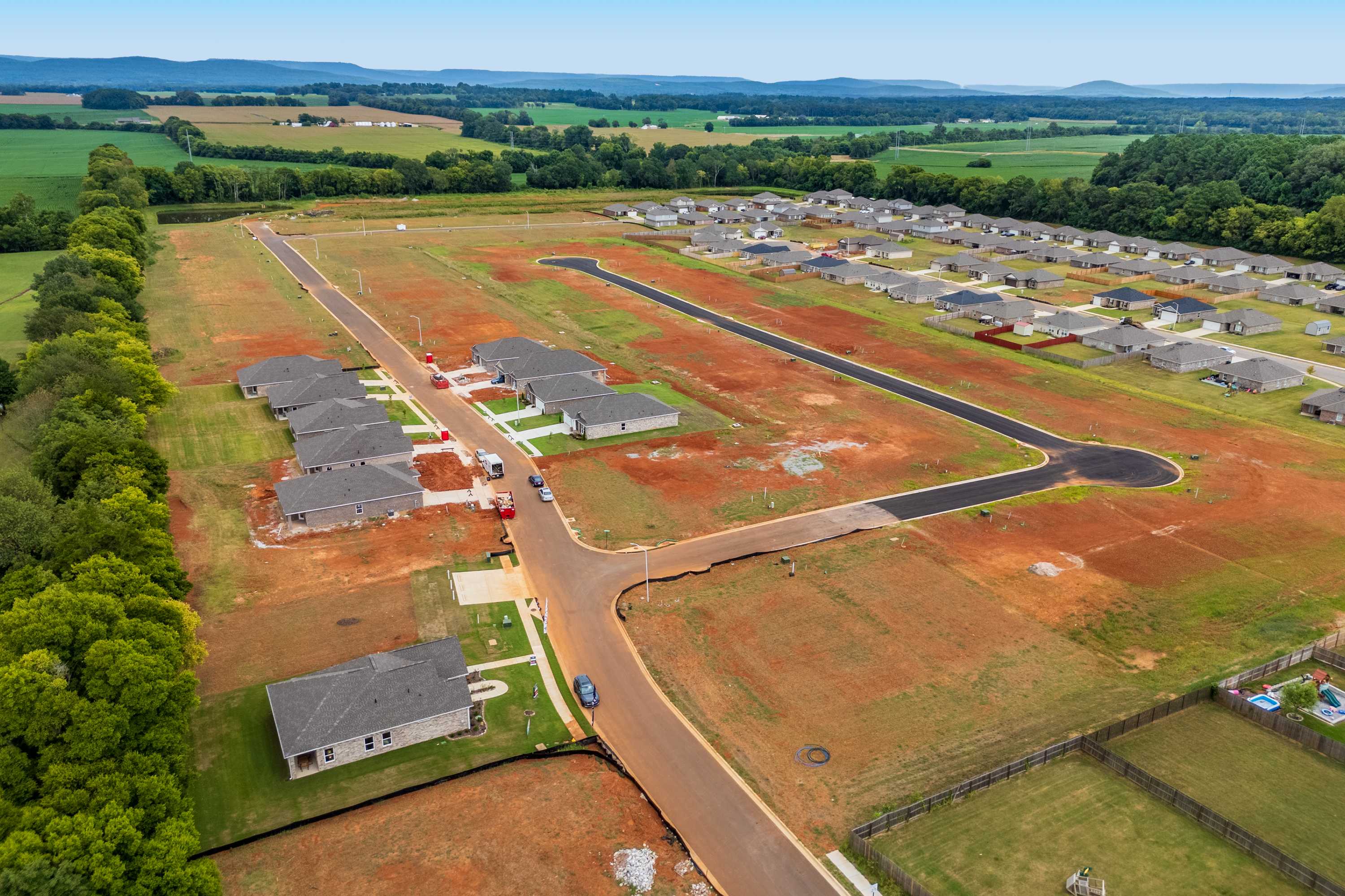 Aerial view of new home construction at Lynn Meadows in Meridianville Alabama by Davidson Homes with dirt roads and wooded surroundings
