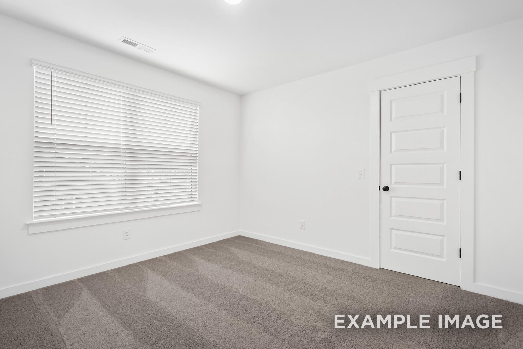 Bright empty bedroom with large window, white blinds, and beige carpet in Davidson Homes Ridgeport C, Gallatin, TN