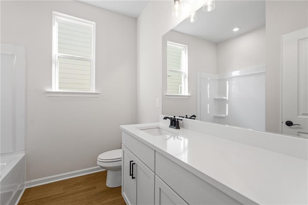 Bright guest bathroom with white vanity, tub shower combo, and large windows in Davidson Homes The Edison A, Loganville, GA