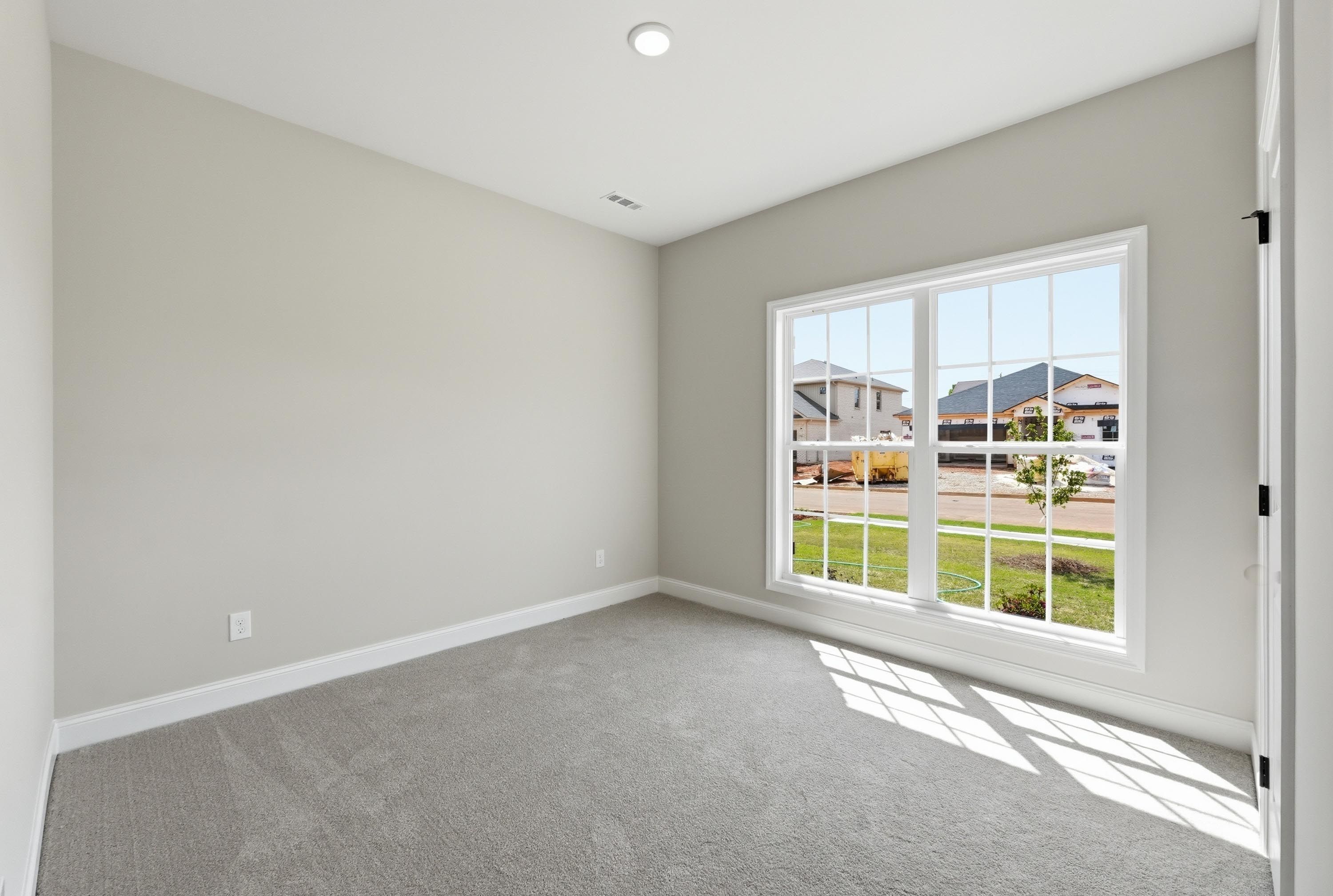 Bright bedroom in The Glen A floor plan by Davidson Homes featuring neutral walls, plush carpet, and large windows.
