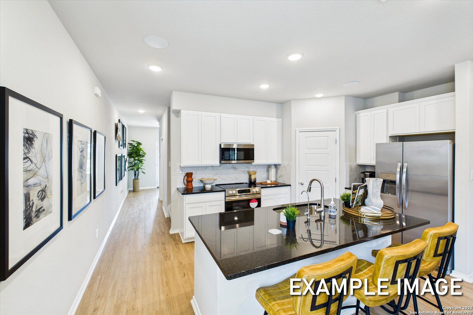 Modern open-concept kitchen with white cabinets, black granite island, stainless appliances, yellow stools in Davidson Homes Sabine B, Agave, San Antonio