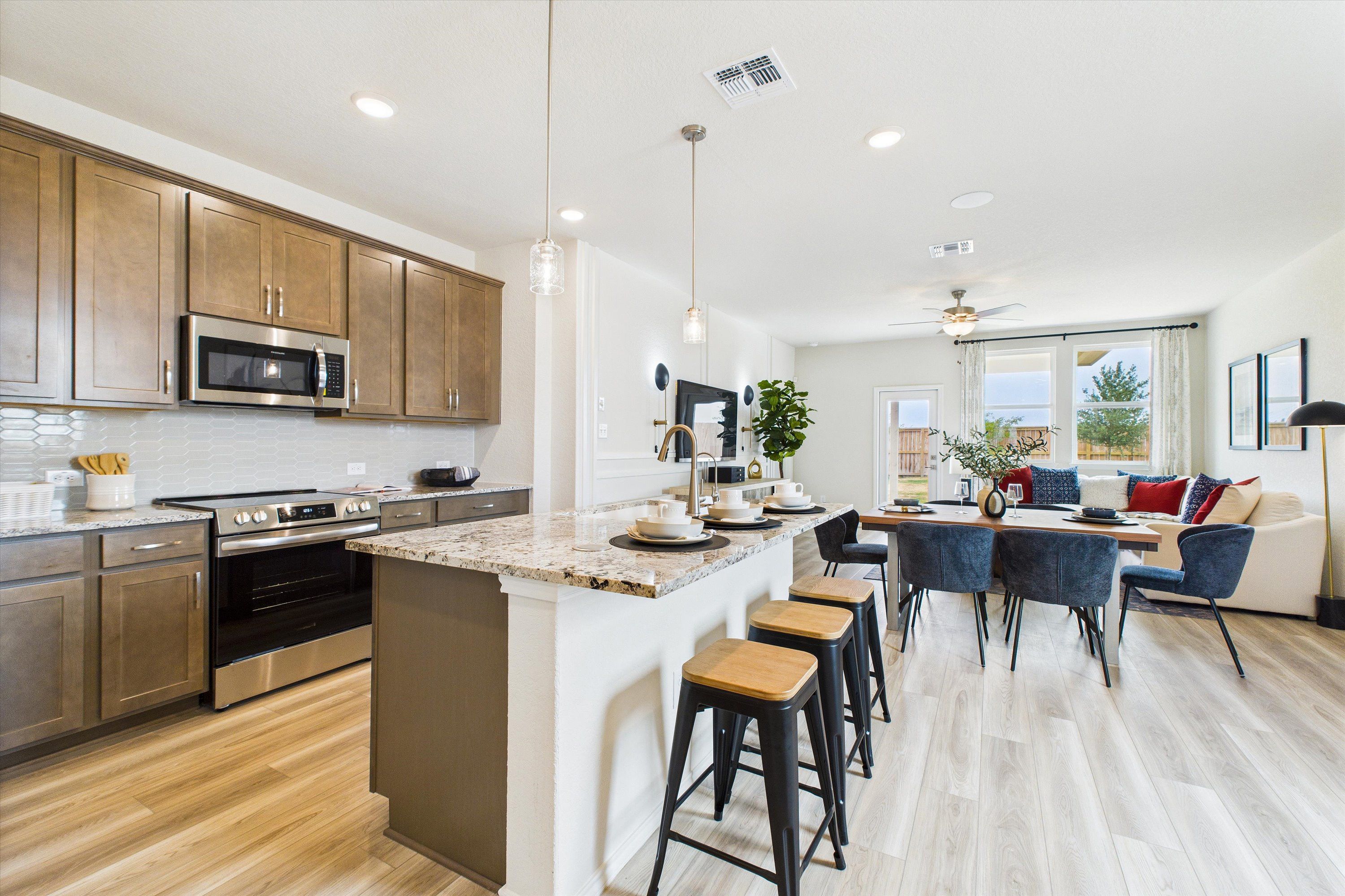 Spacious open-concept kitchen dining at Fairway Crossing in Converse TX with granite island, hardwood floors, pendant lights