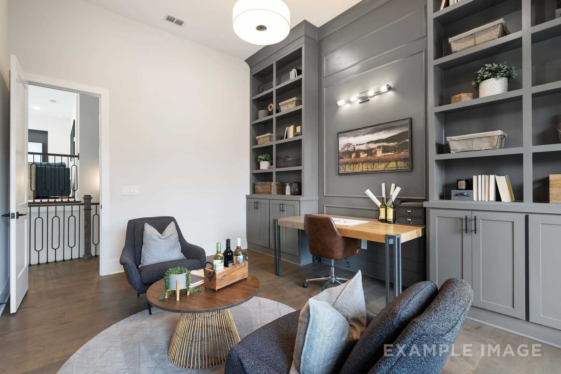Spacious home office at Manor Estates in Marietta GA with gray built-in bookshelves, wooden desk, accent chairs