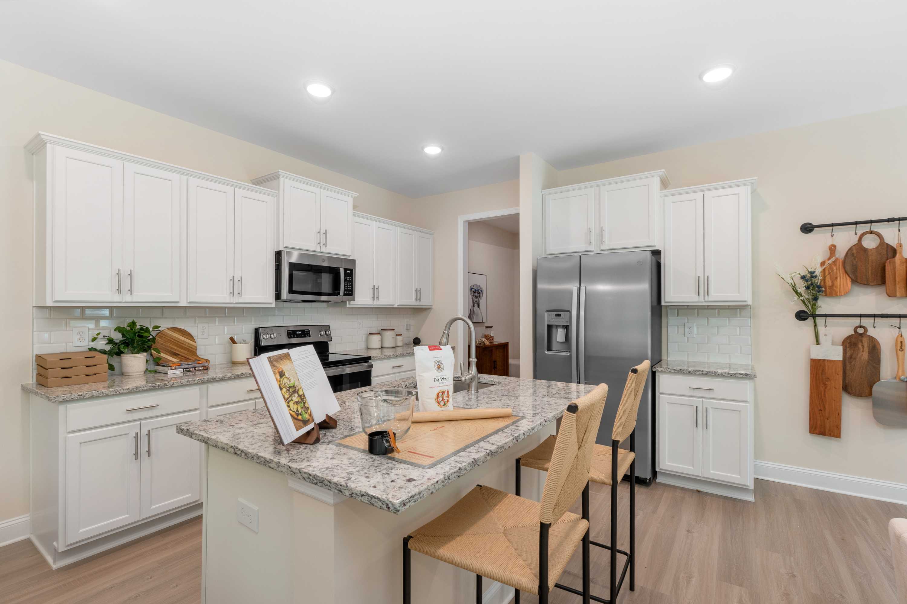 Modern kitchen in Pavilion Huntsville AL with white shaker cabinets, granite island, stainless appliances and hardwood floors by Davidson Homes