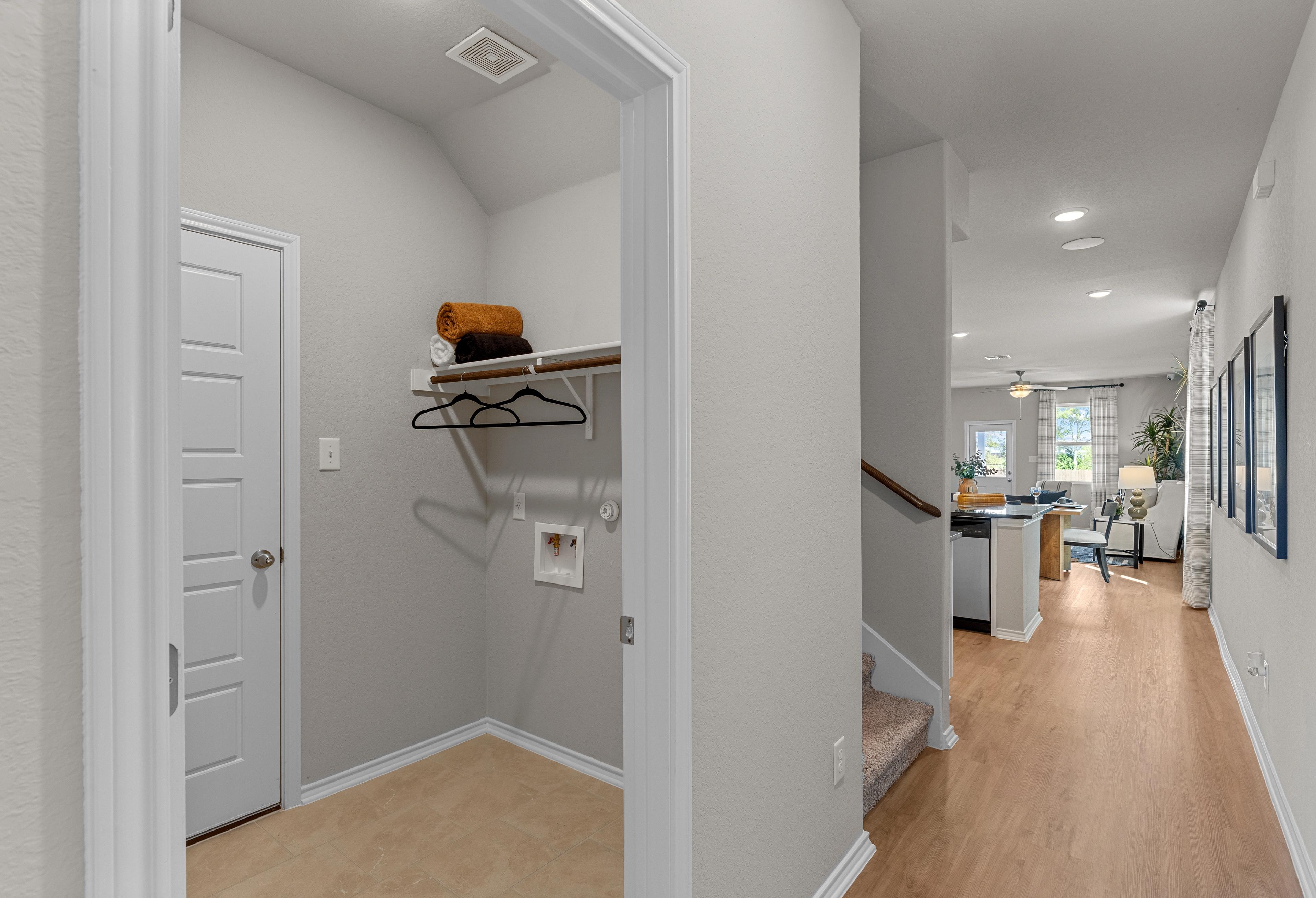 Spacious laundry room in The Sabine A home with built-in shelves, towels, washer space, and open view to kitchen hallway