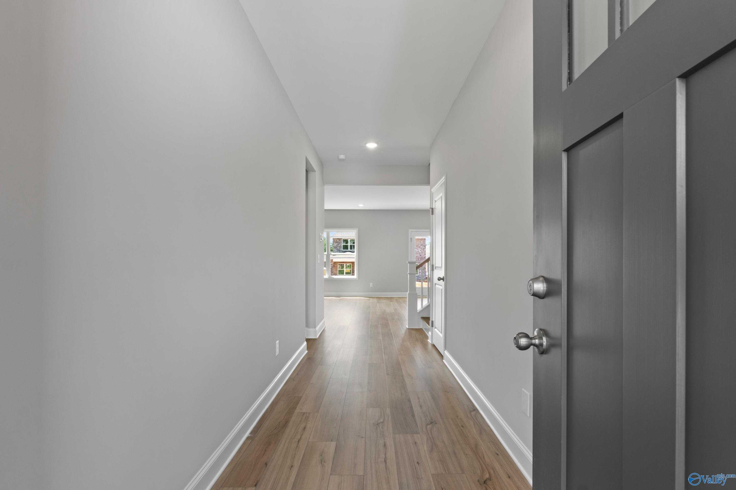 Spacious hallway with gray walls, hardwood floors, and bedroom doors in 5-bedroom Davidson Homes Chelsea B, New Market, AL