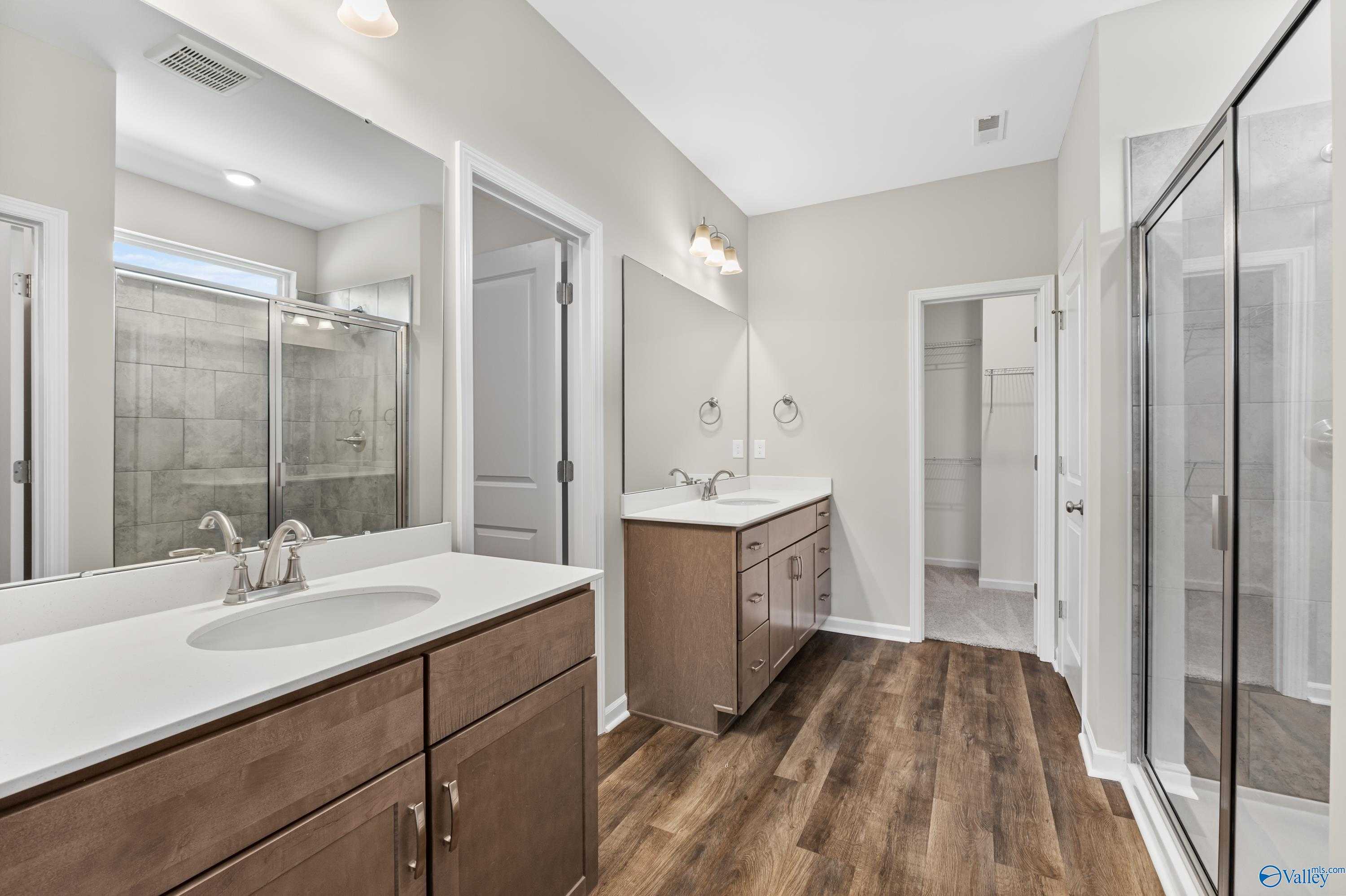 Modern master bathroom featuring double vanity, glass shower enclosure, and luxury wood flooring in Davidson Homes The Haven, Huntsville