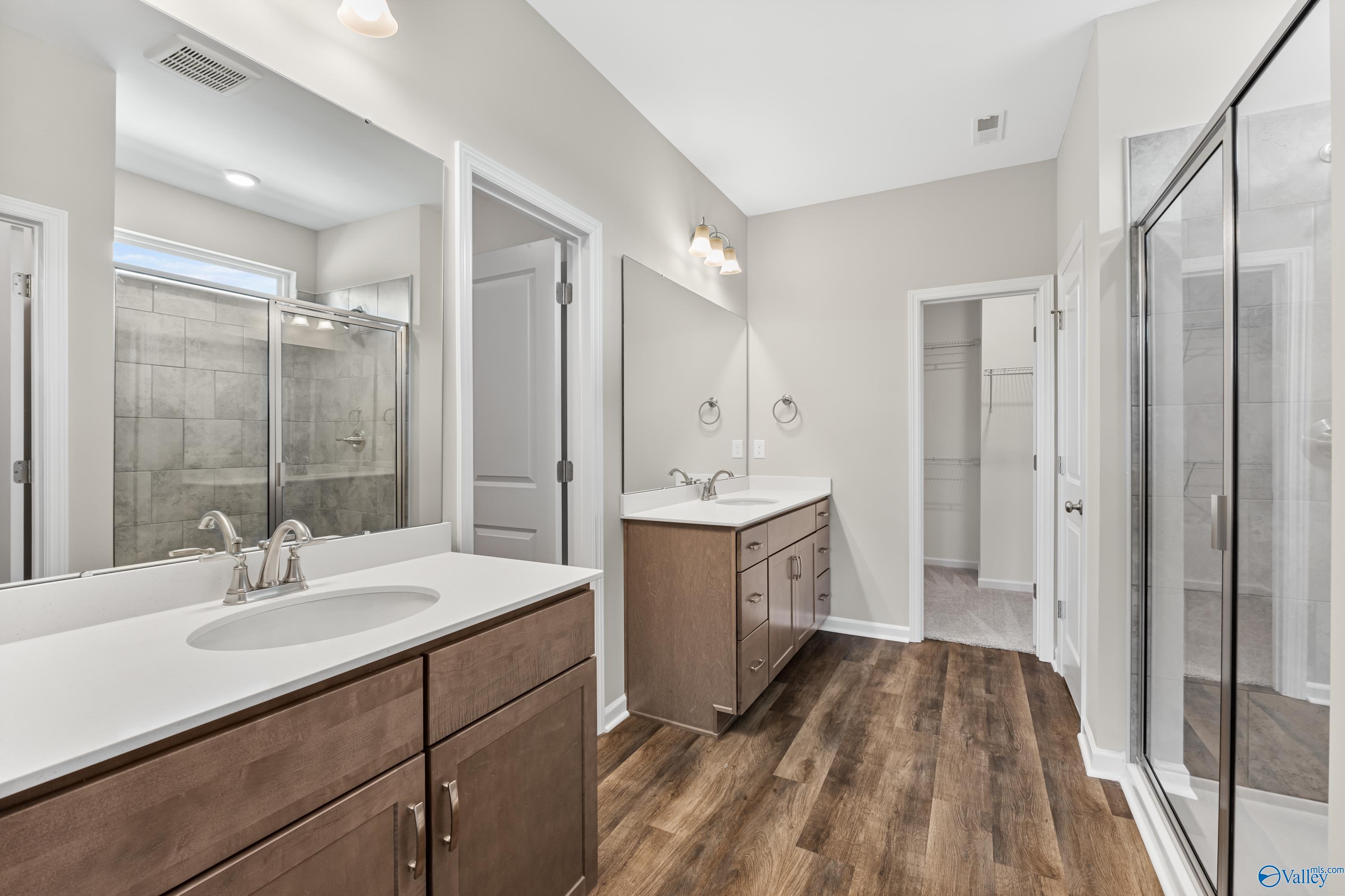 Modern master bathroom featuring double vanity, glass shower enclosure, and luxury wood flooring in Davidson Homes The Haven, Huntsville