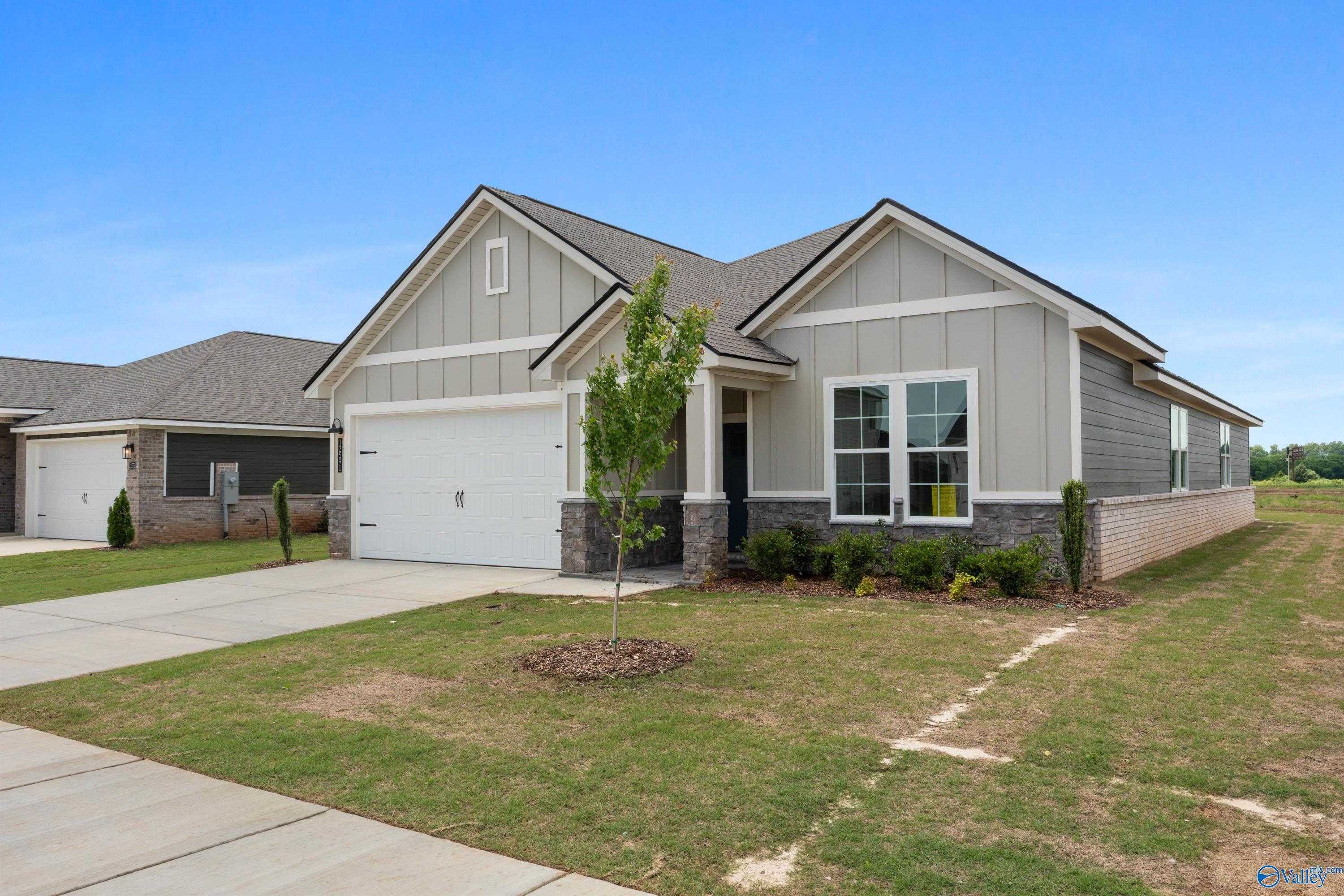 Modern gray 1-story Davidson Homes The Orion with 2-car garage, front windows, young tree, shrubs, and green lawn in Anderson Farm, Athens AL