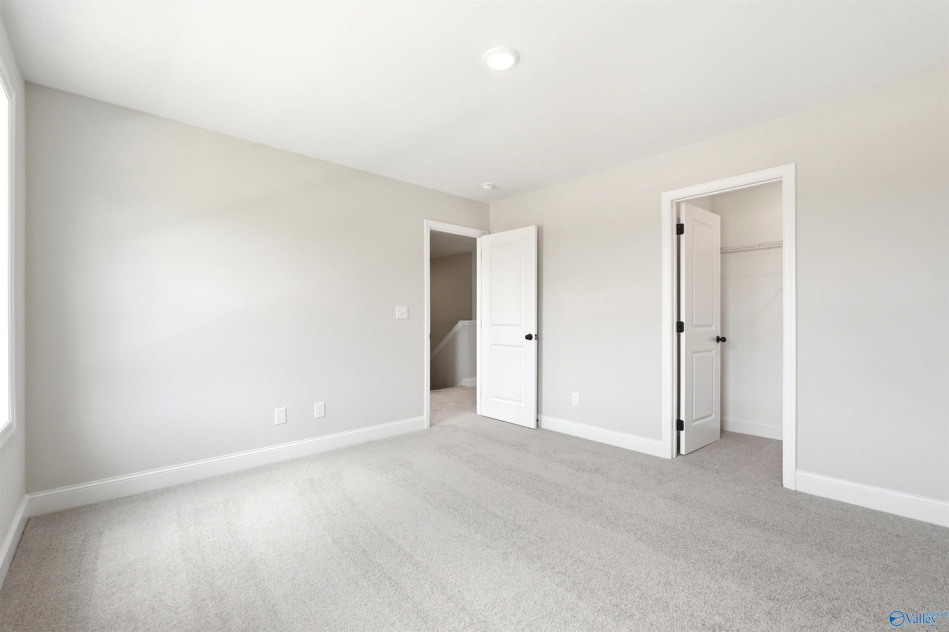 Bright, neutral-toned secondary bedroom with plush carpeting and walk-in closet in The Shelby A home, Wood Trail, Toney.