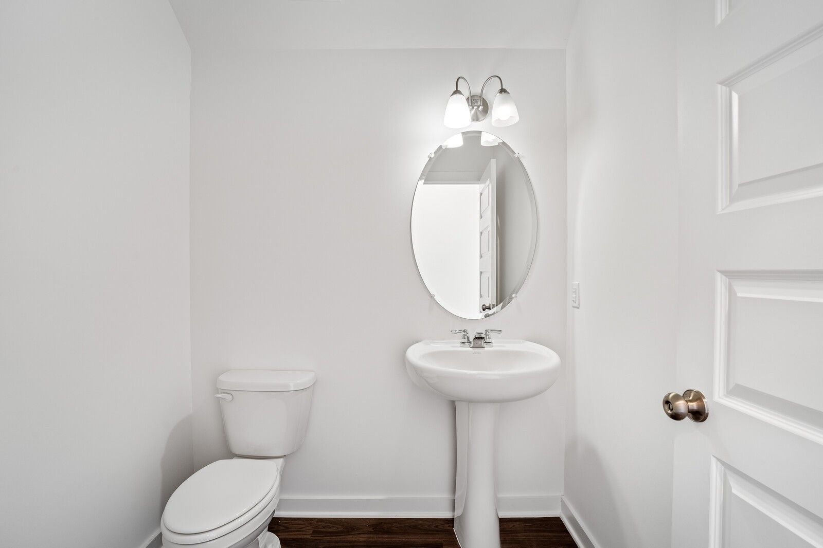 Elegant powder room featuring pedestal sink, oval mirror, sconce lights in Davidson Homes The Logan C, Sage Farms, White House, Tennessee