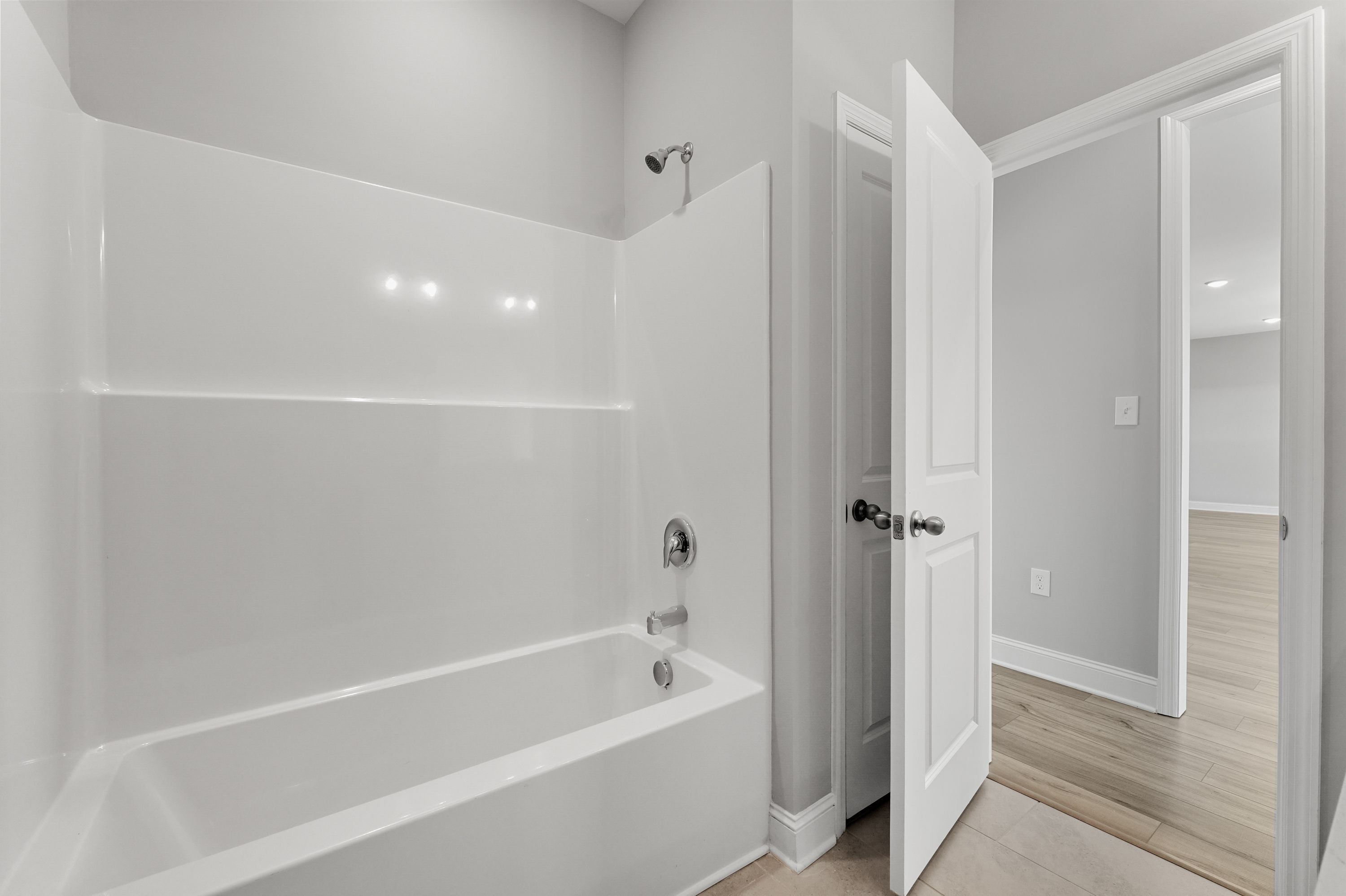 Spacious master bathroom in The Valencia with white subway tile shower, soaking tub, and gray walls