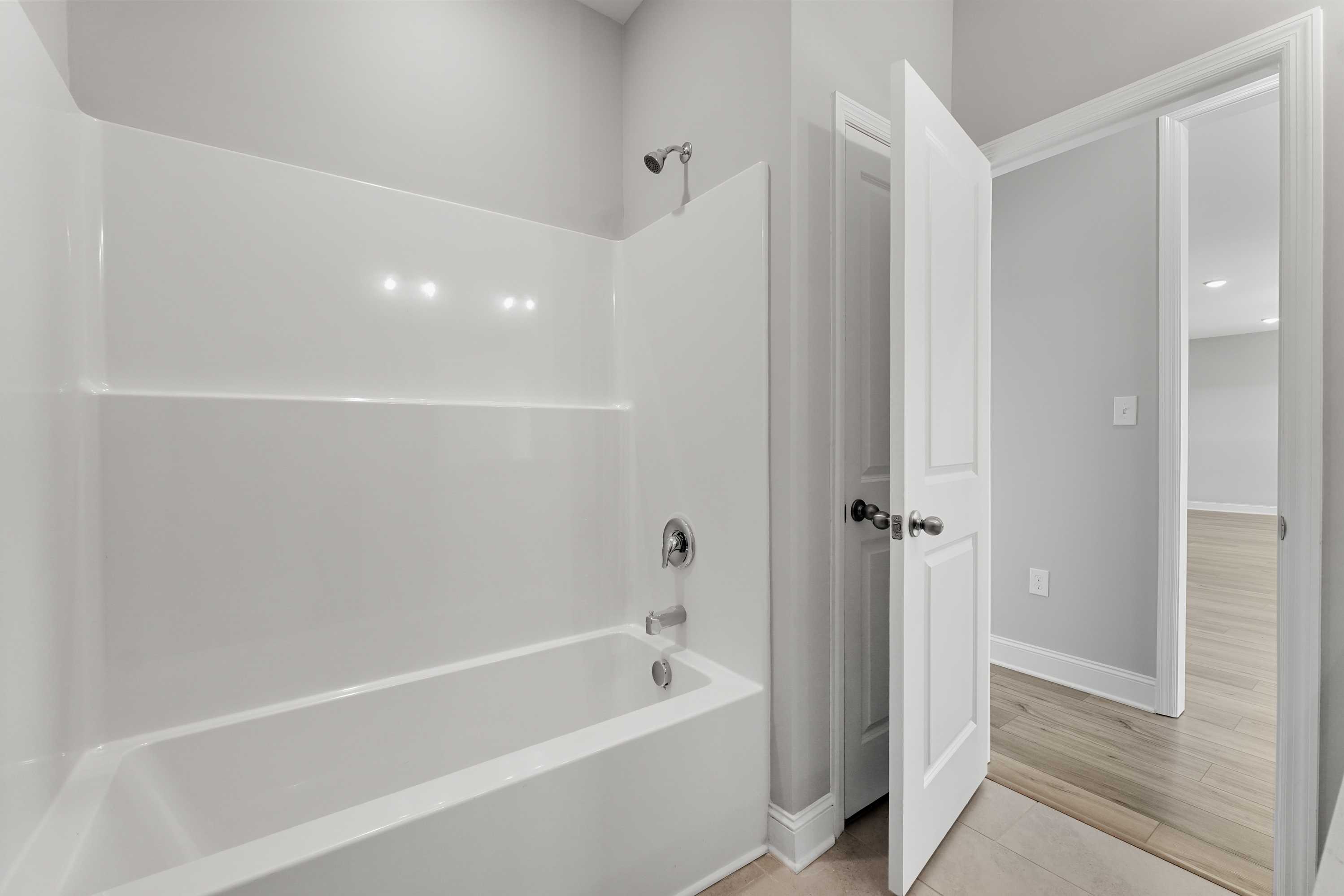 Spacious master bathroom in The Valencia with white subway tile shower, soaking tub, and gray walls