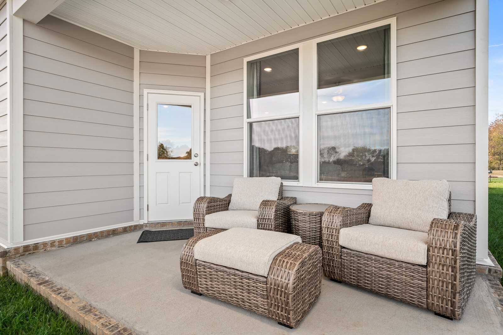Covered patio with wicker chairs and ottoman at Sage Farms in White House, Tennessee by Davidson Homes