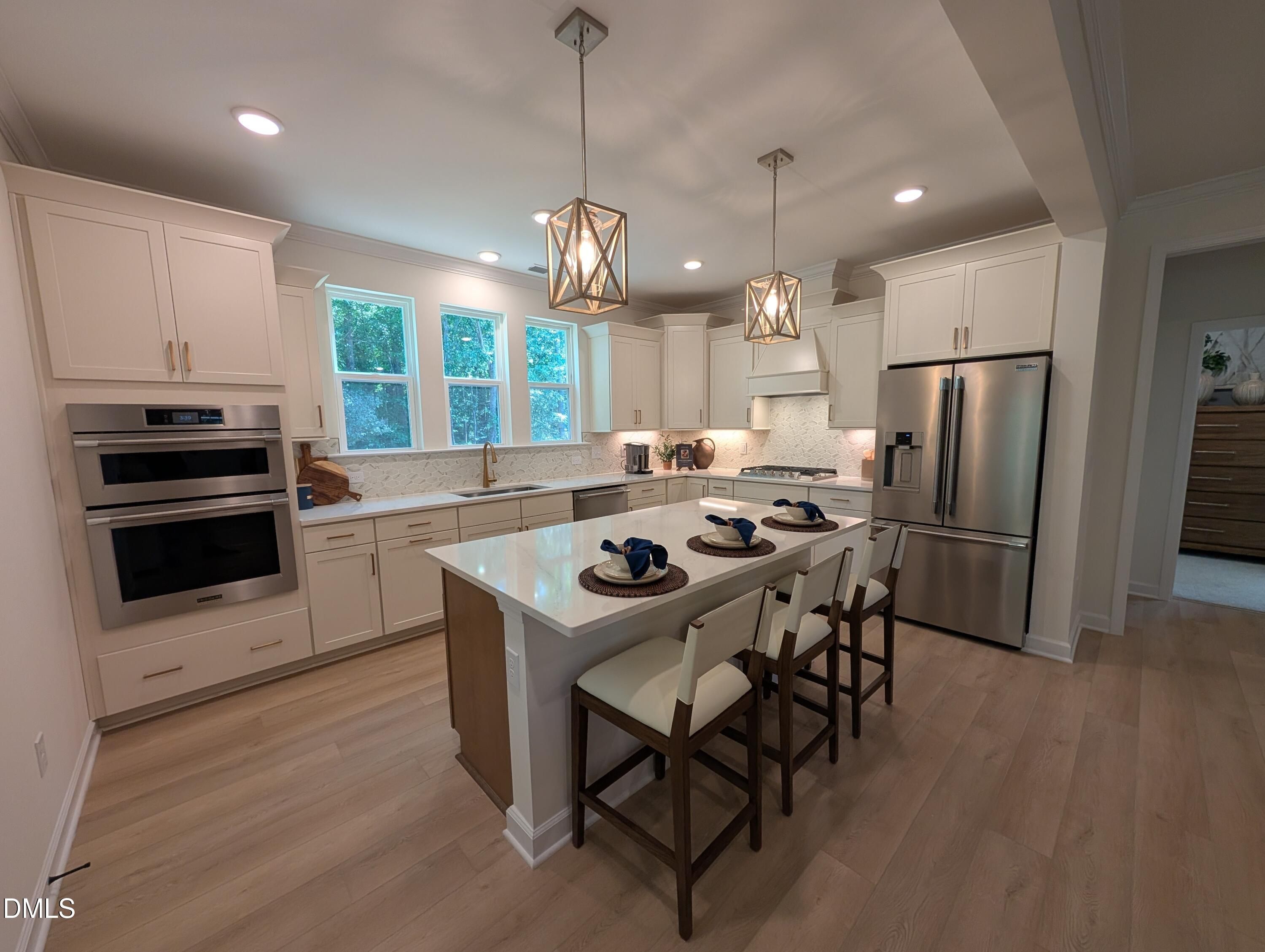 Modern kitchen with large island, stainless steel appliances, and pendant lighting in The Aspen B at Wendell Ridge, NC.