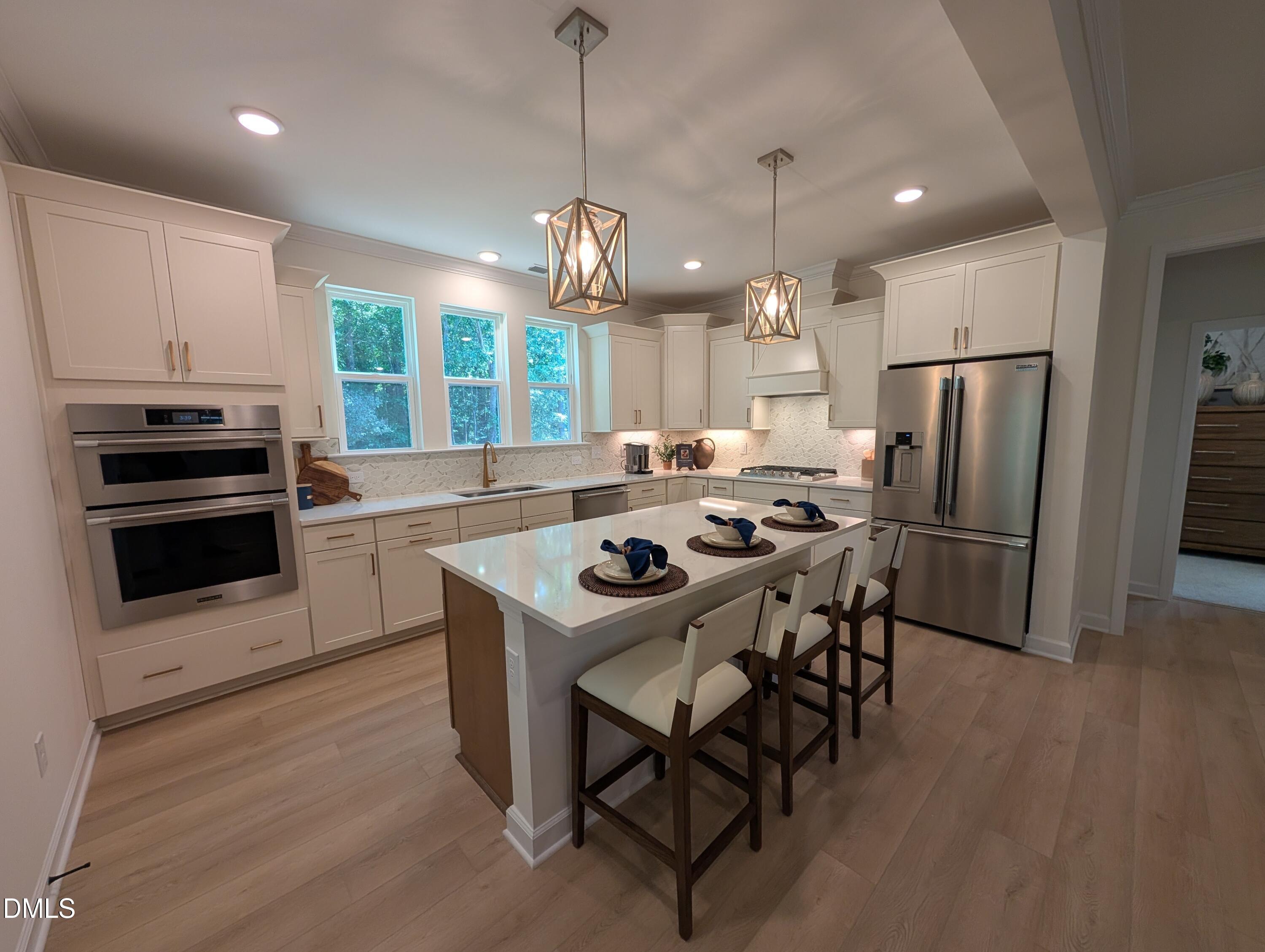 Modern kitchen with large island, stainless steel appliances, and pendant lighting in The Aspen B at Wendell Ridge, NC.