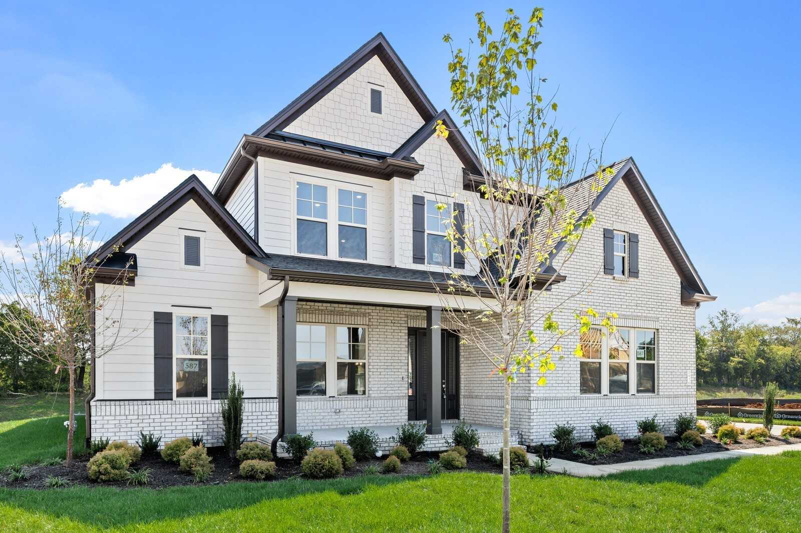 Two-story white brick Davidson Homes Albany A with black trim, covered porch, and landscaped yard in Shelton Square, Murfreesboro, TN