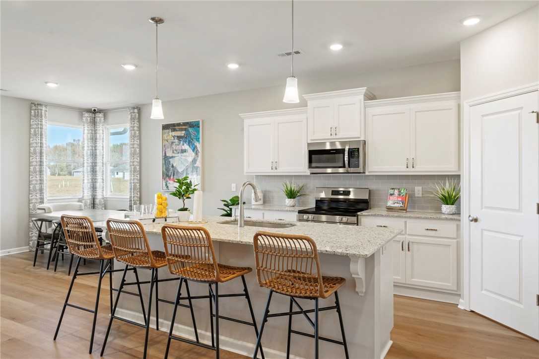 Modern open-concept kitchen with white shaker cabinets, granite island, stainless appliances in Davidson Homes The Phoenix B, Opelika