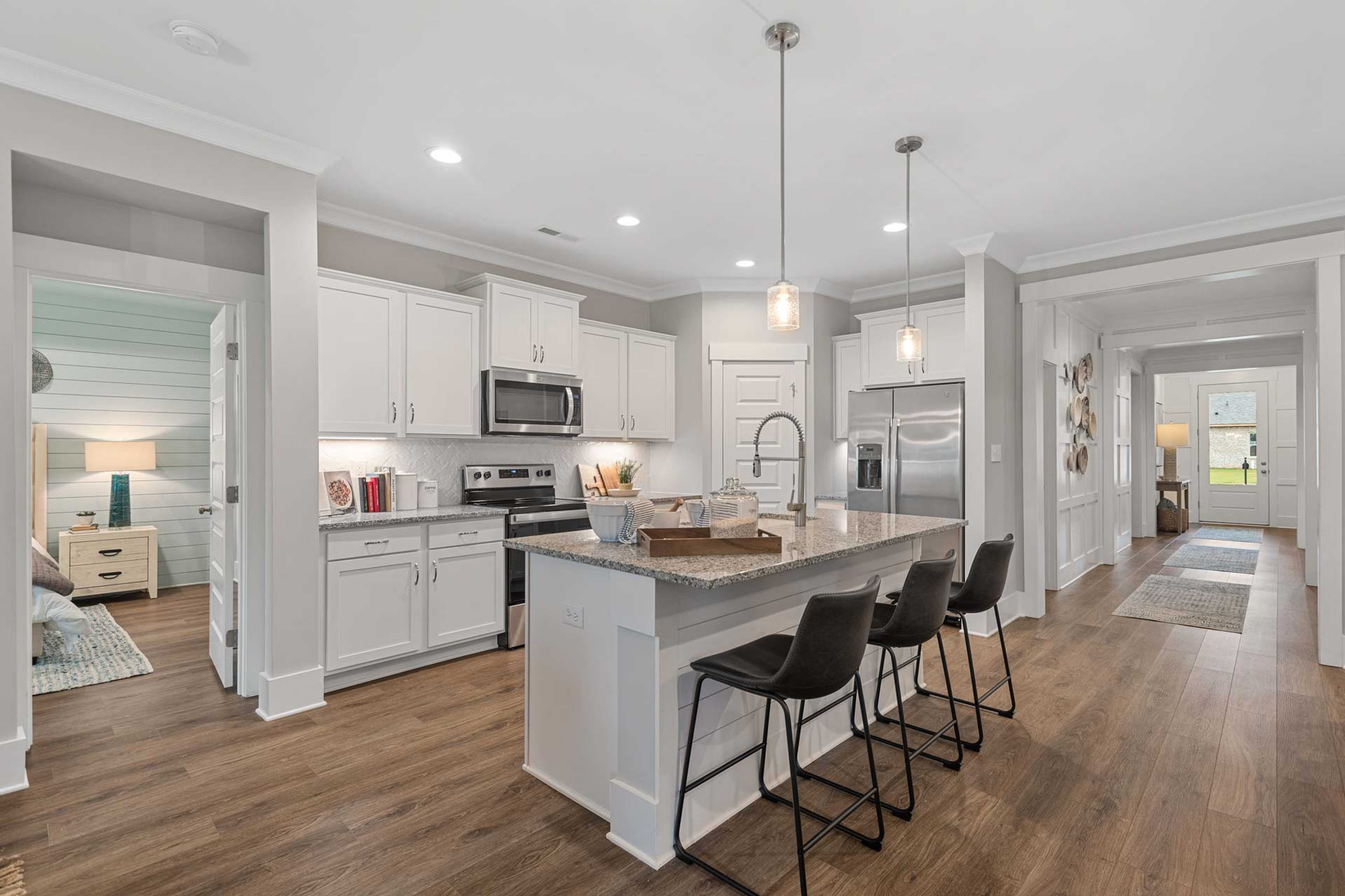 Modern open-concept kitchen at Monteagle Cove in Owens Cross Roads AL featuring white shaker cabinets, large island, stainless appliances, and hardwood floors