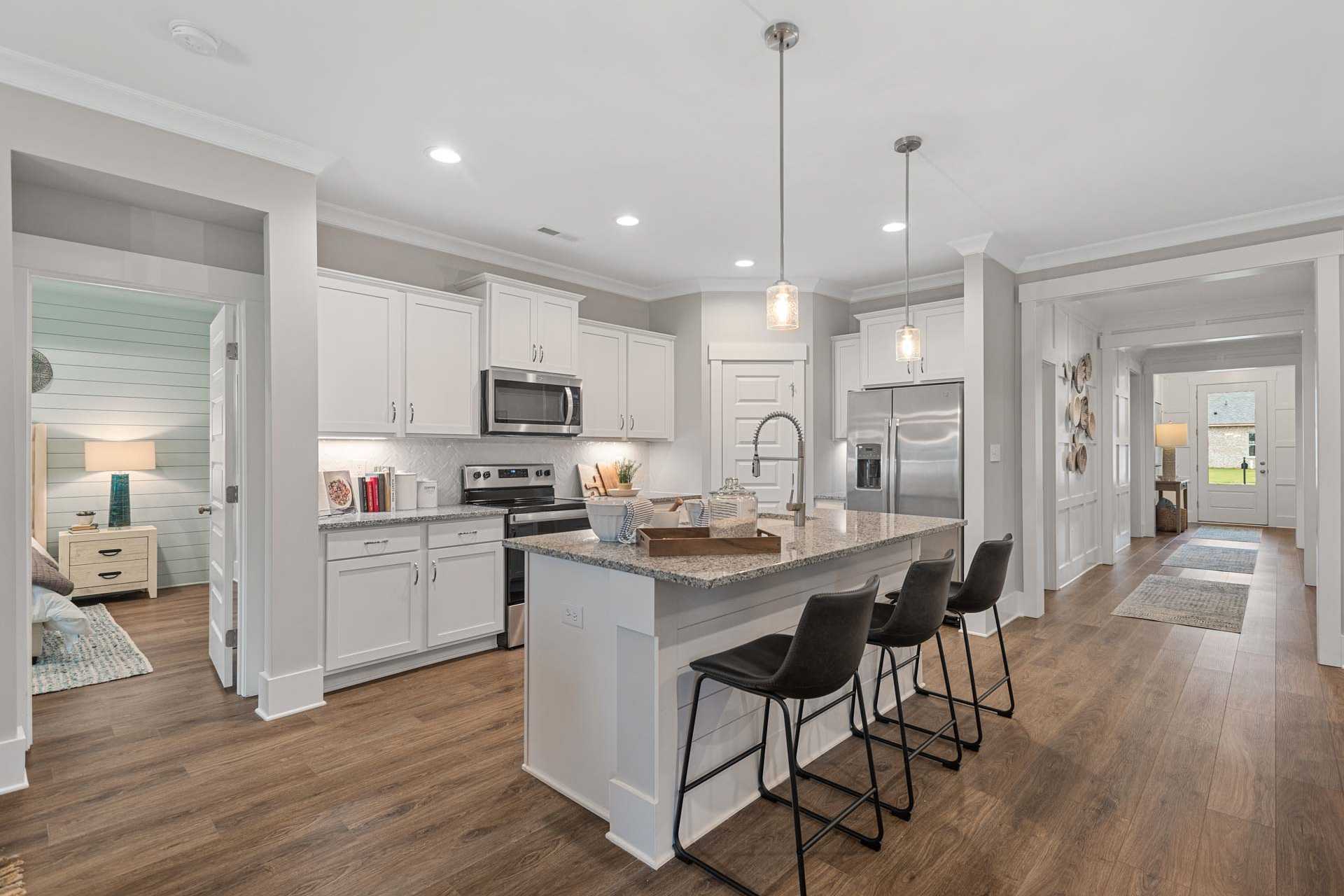 Modern open-concept kitchen at Monteagle Cove in Owens Cross Roads AL featuring white shaker cabinets, large island, stainless appliances, and hardwood floors
