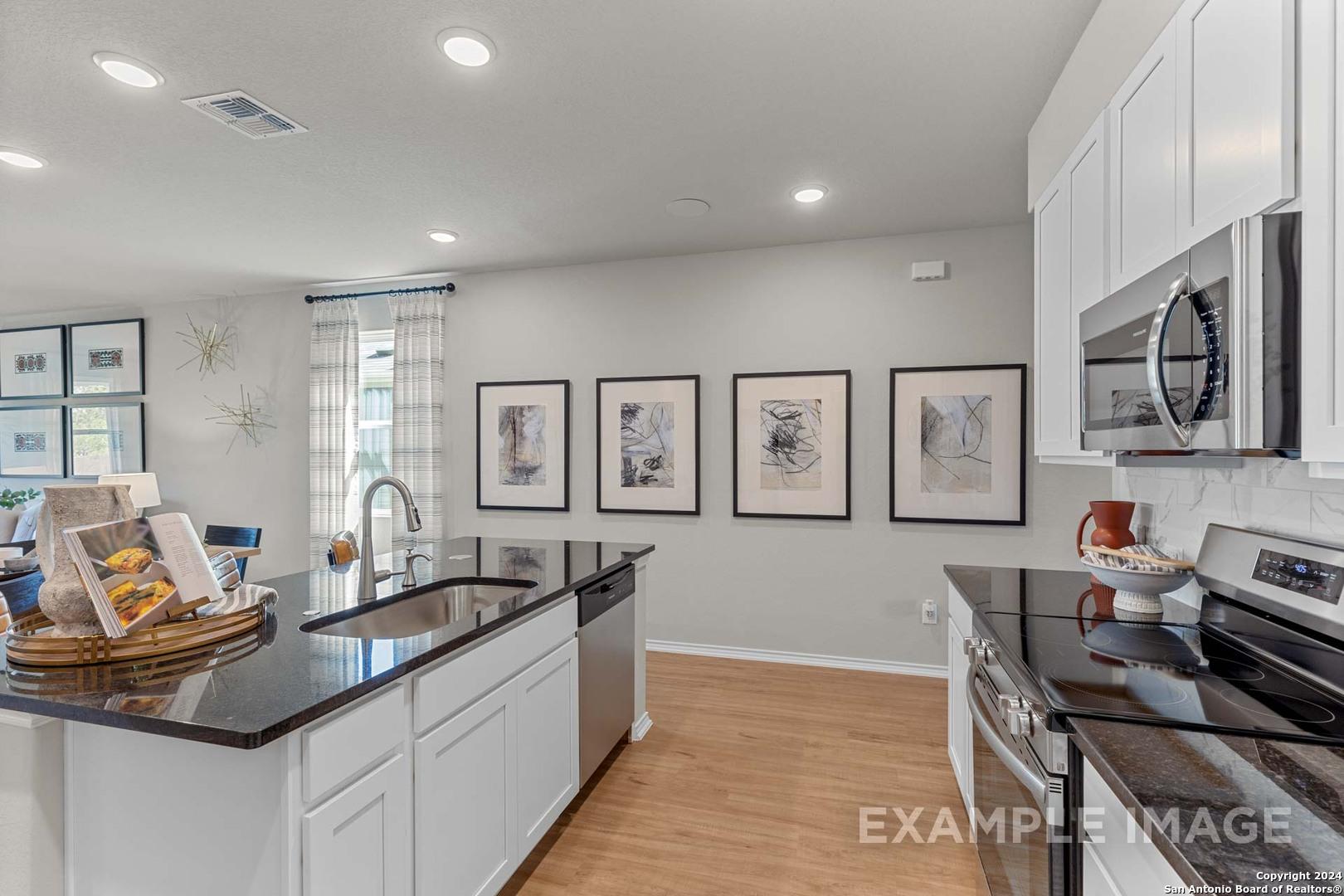 Modern kitchen with white cabinets, black granite island, stainless appliances in The Sabine B, Applewhite Meadows, San Antonio