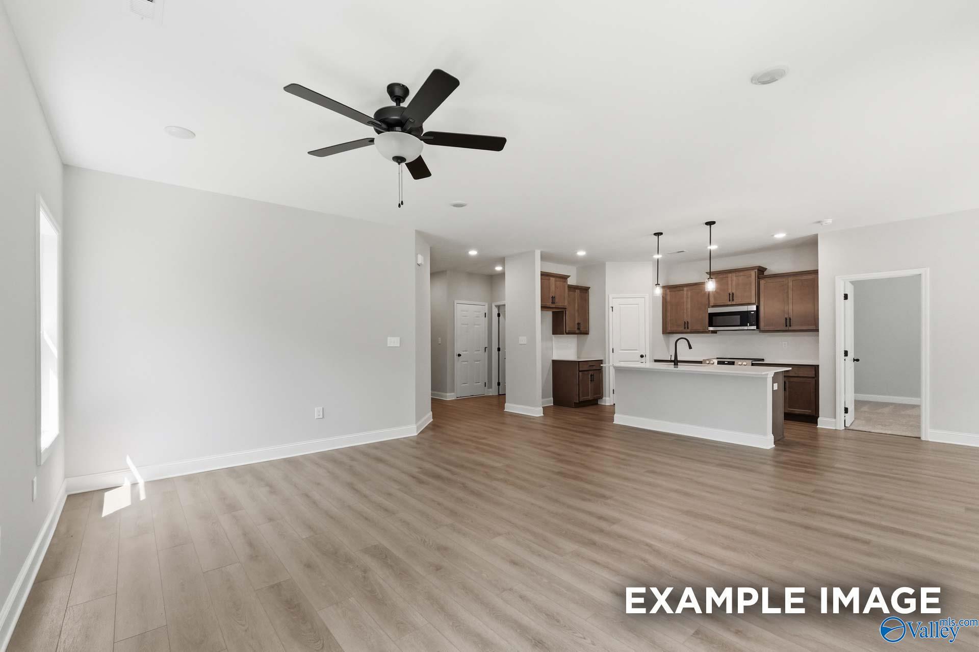 Open-concept living room and kitchen with wood flooring and island in The Franklin C floor plan at The Highlands, Arab, AL.