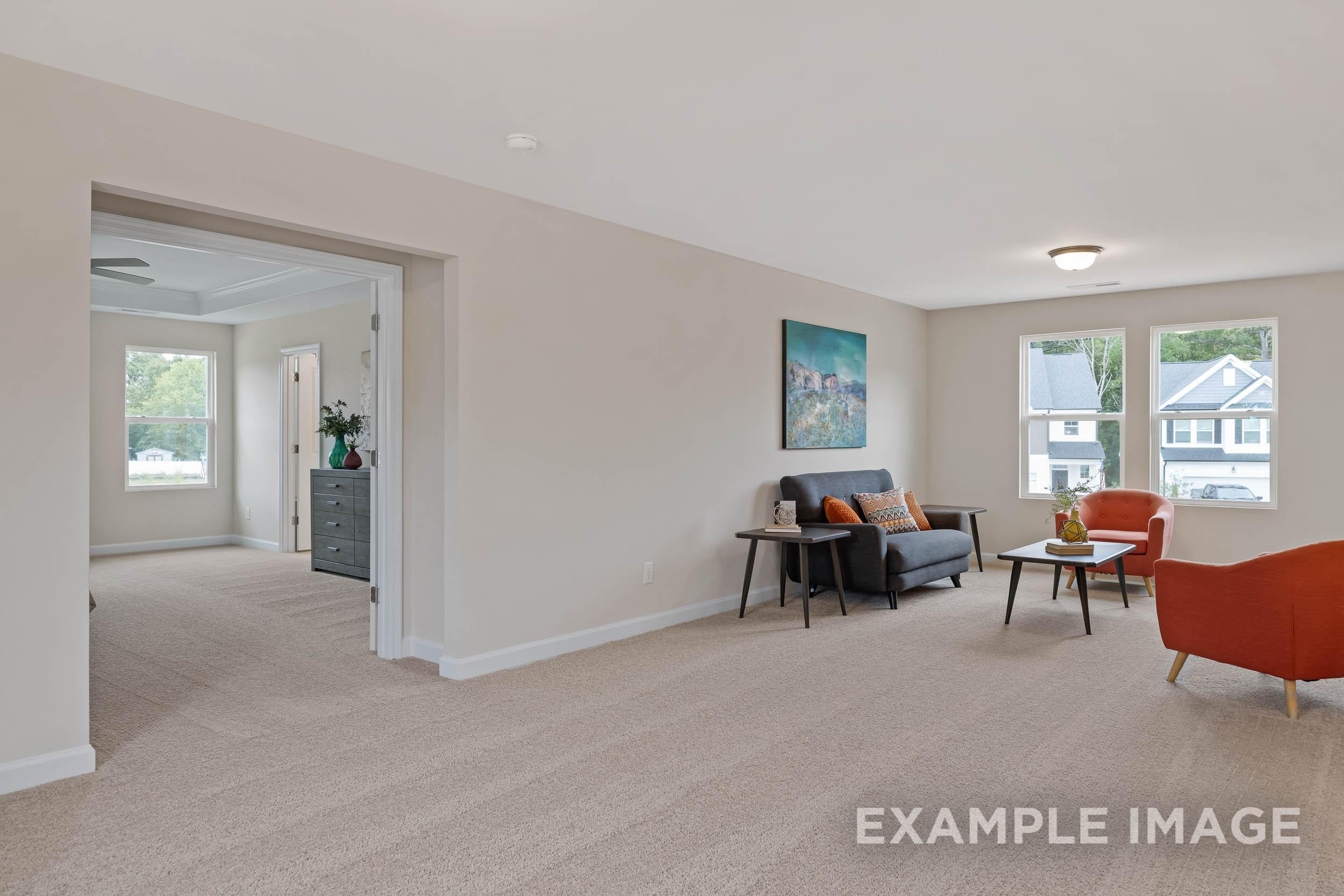 Spacious living room in The Preston B with gray loveseat, orange armchair, abstract art, and open archway in Wendell NC home