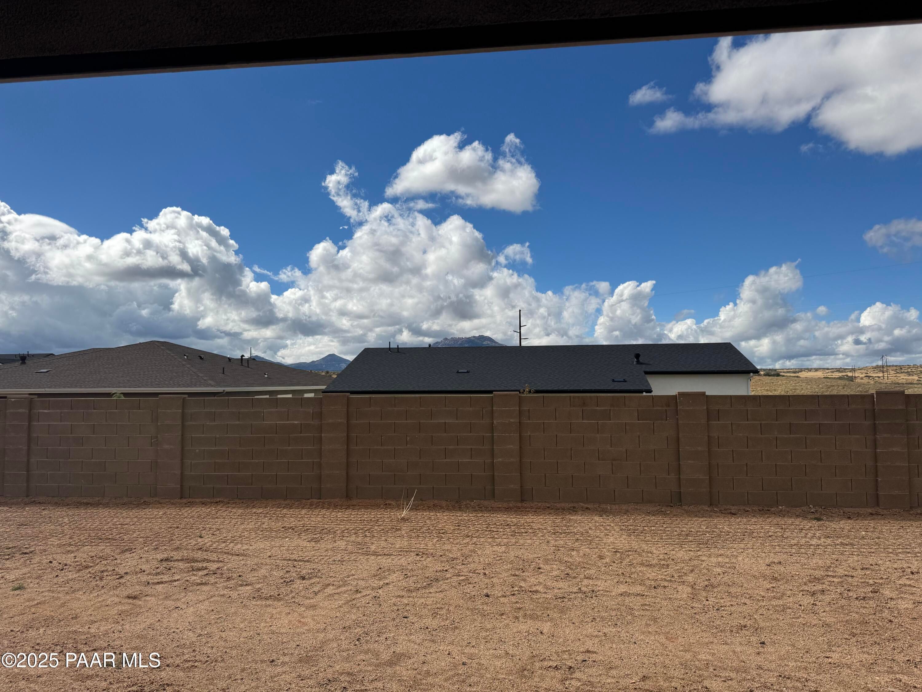 Covered back patio overlooking fenced dirt backyard with mountain views in Davidson Homes The Monarch A, Prescott, Arizona