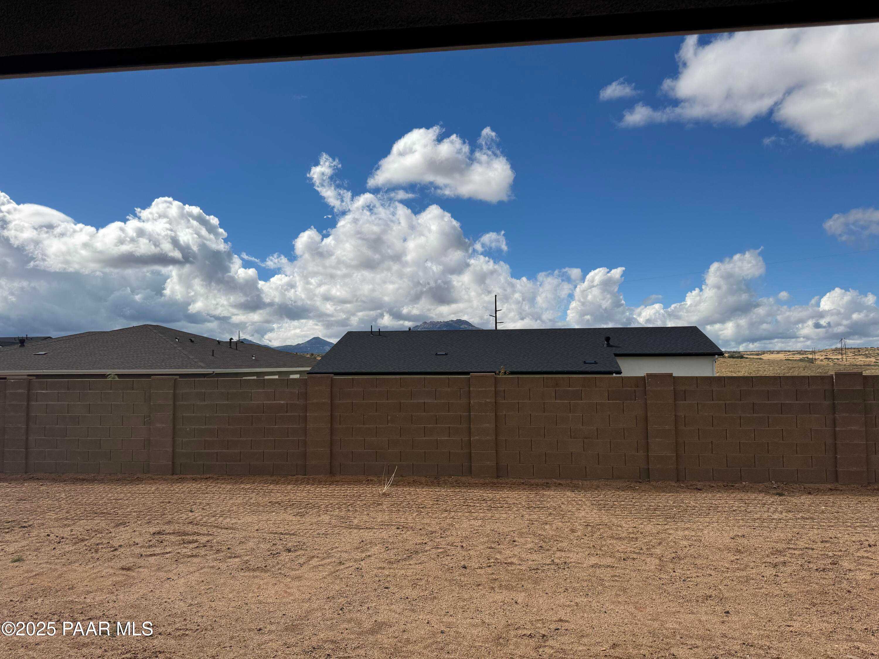 Covered back patio overlooking fenced dirt backyard with mountain views in Davidson Homes The Monarch A, Prescott, Arizona
