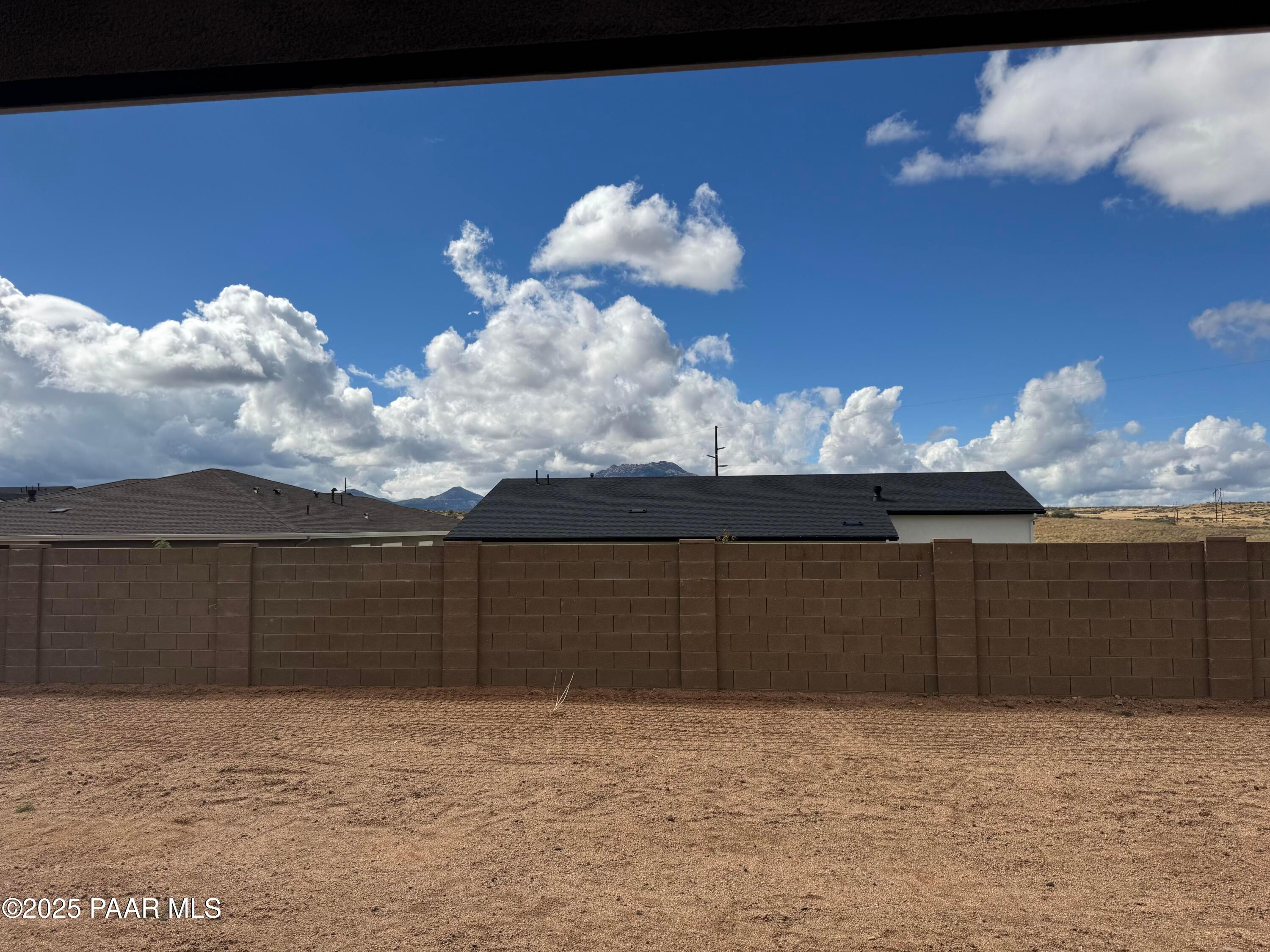 Covered back patio overlooking fenced dirt backyard with mountain views in Davidson Homes The Monarch A, Prescott, Arizona