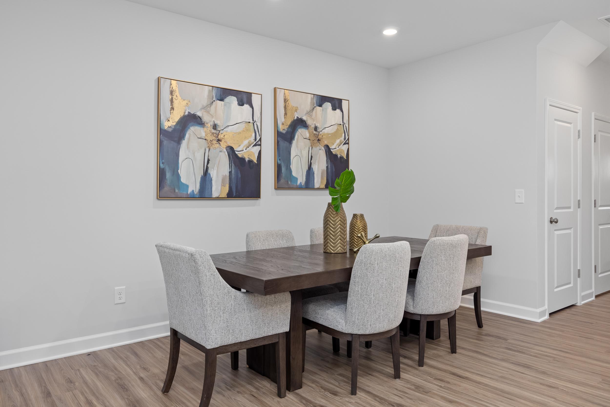 Modern dining room in The Warren featuring a dark wood table, upholstered chairs, and abstract wall art.