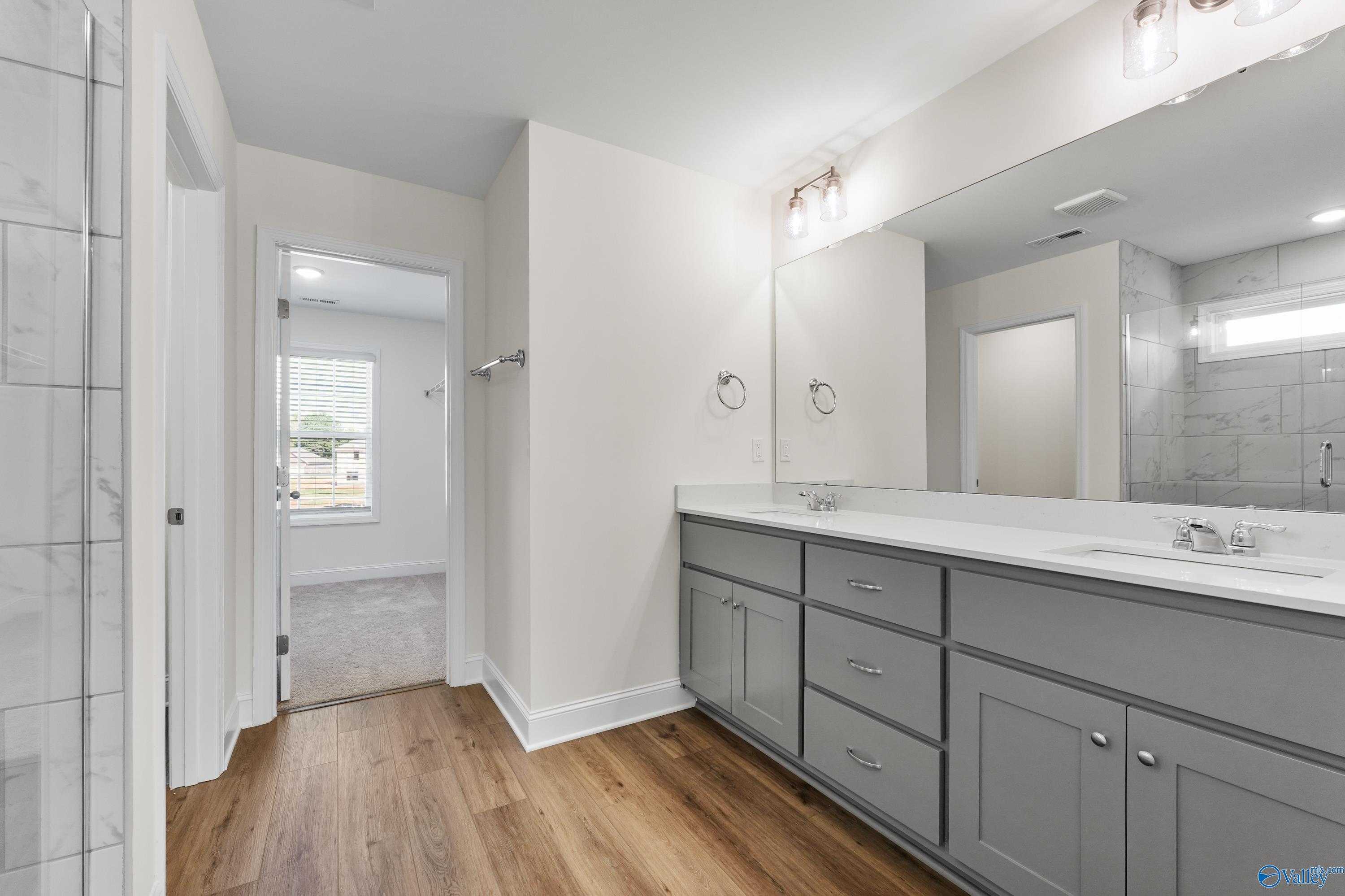 Modern master bathroom with double gray vanity, white quartz counters, and frameless glass shower in Davidson Homes The Shelby A, Athens, Alabama
