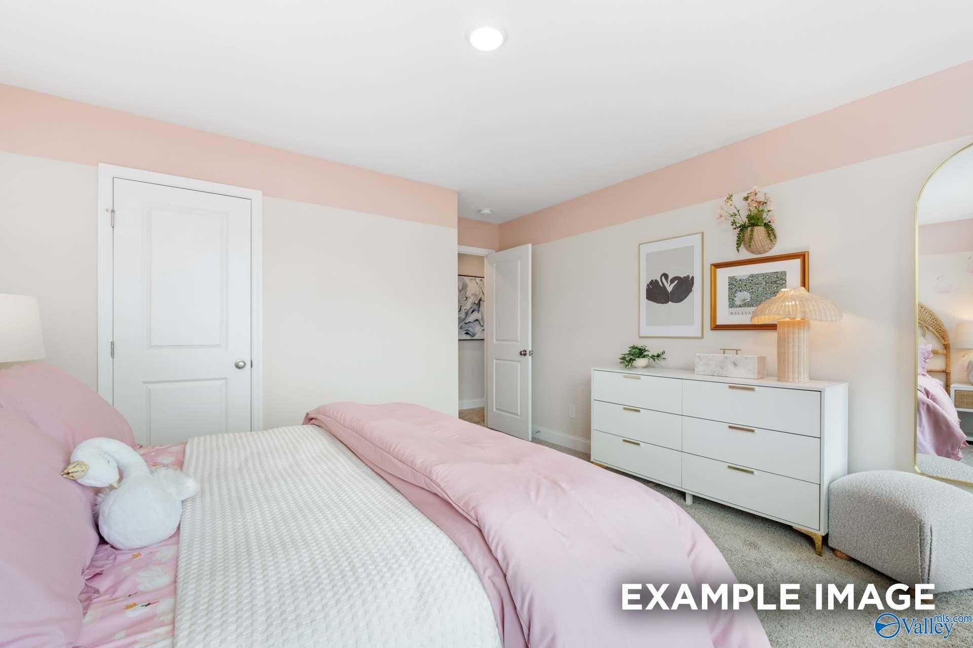 Charming secondary bedroom with pink bedding, white dresser, gold mirror, and en-suite bath in Davidson Homes The Camden B, Huntsville