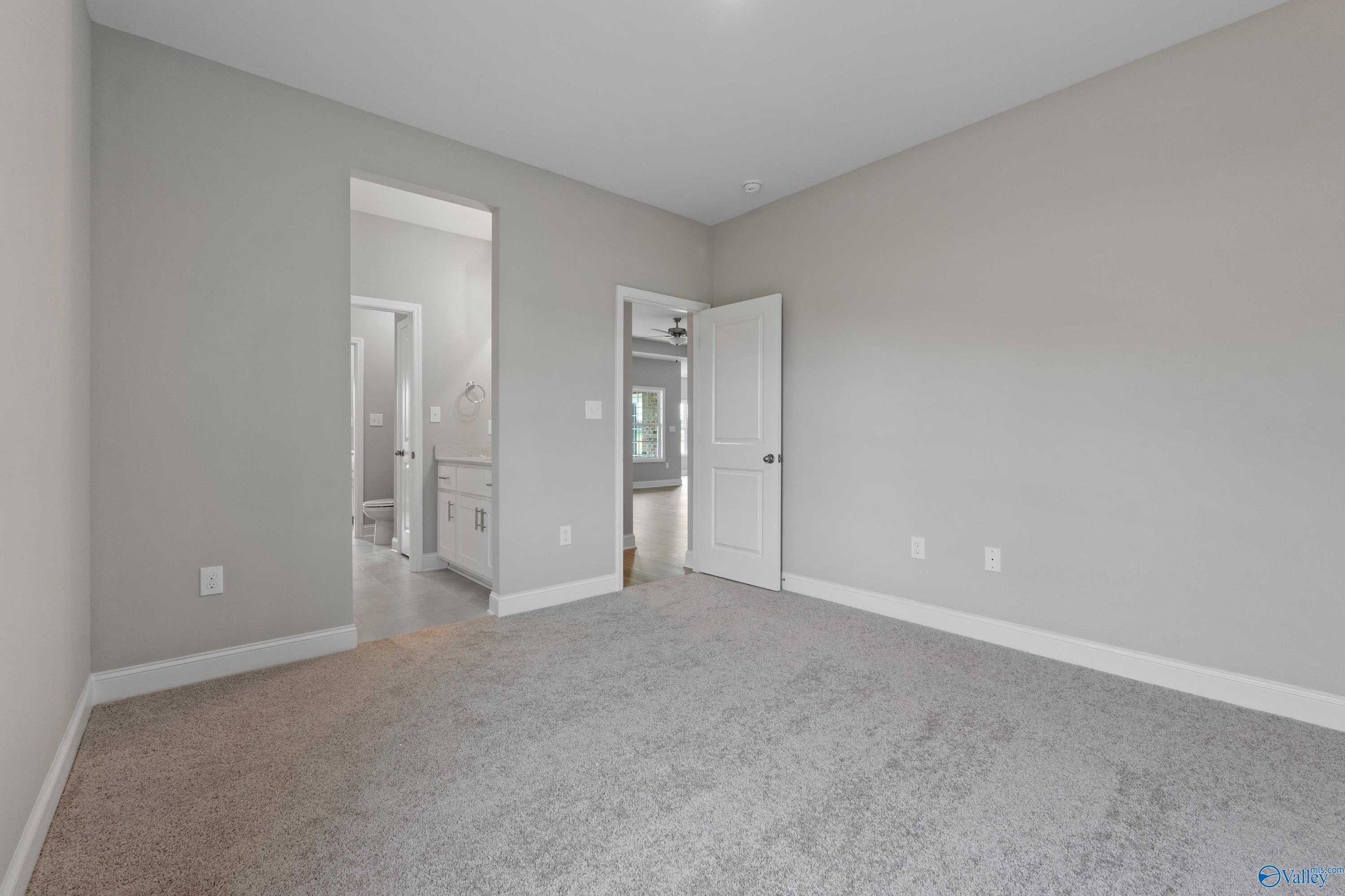 Spacious secondary bedroom with gray walls, carpet flooring, and en-suite bathroom in Davidson Homes The Finleigh, Meridianville, Alabama