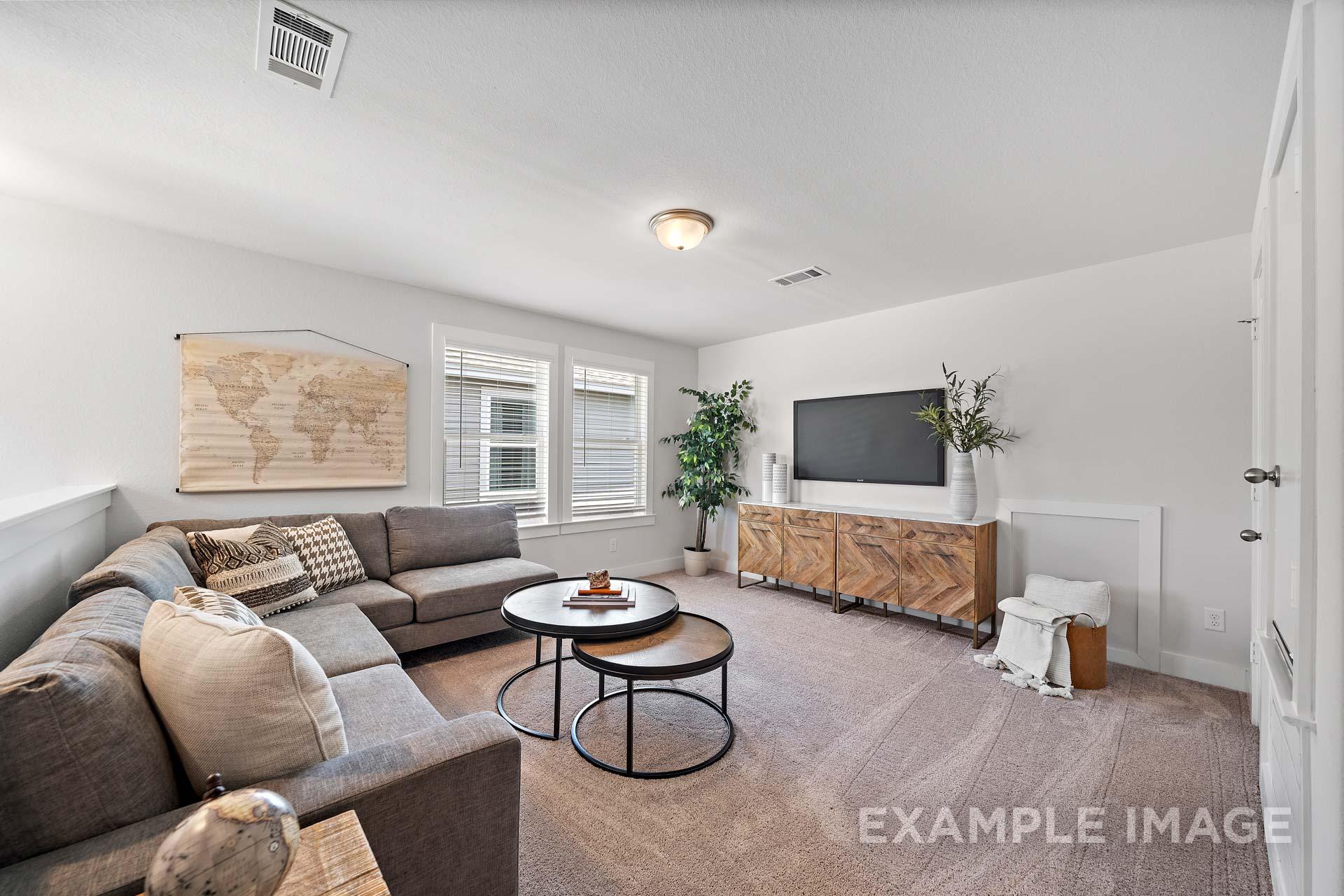 Spacious living room in The Rose B home design with gray L-shaped sofa, nested coffee tables, TV on wood console, world map art