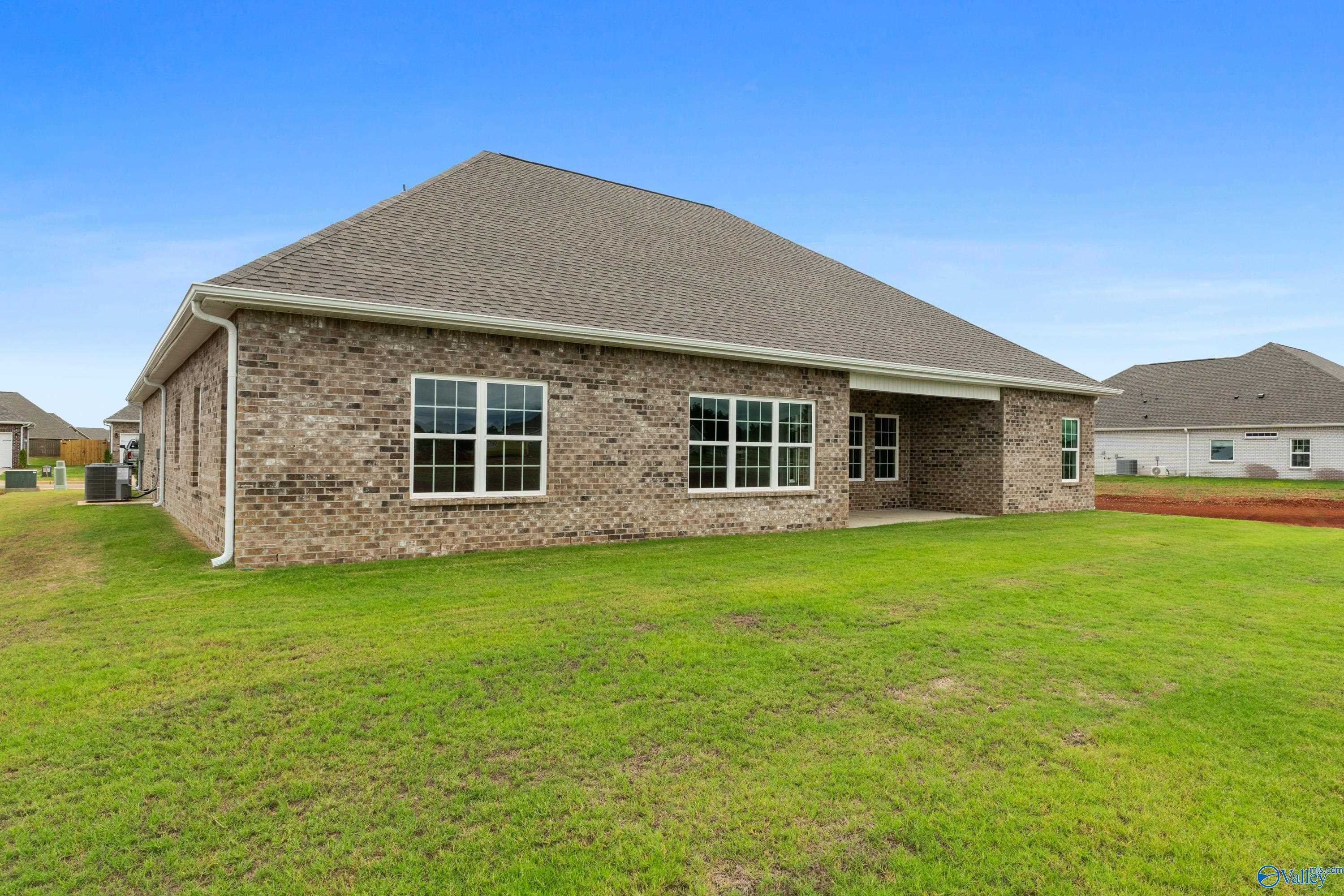 Brick ranch-style Finleigh home exterior with gabled roof, large windows, covered patio, and lush green lawn in Briercreek, Meridianville