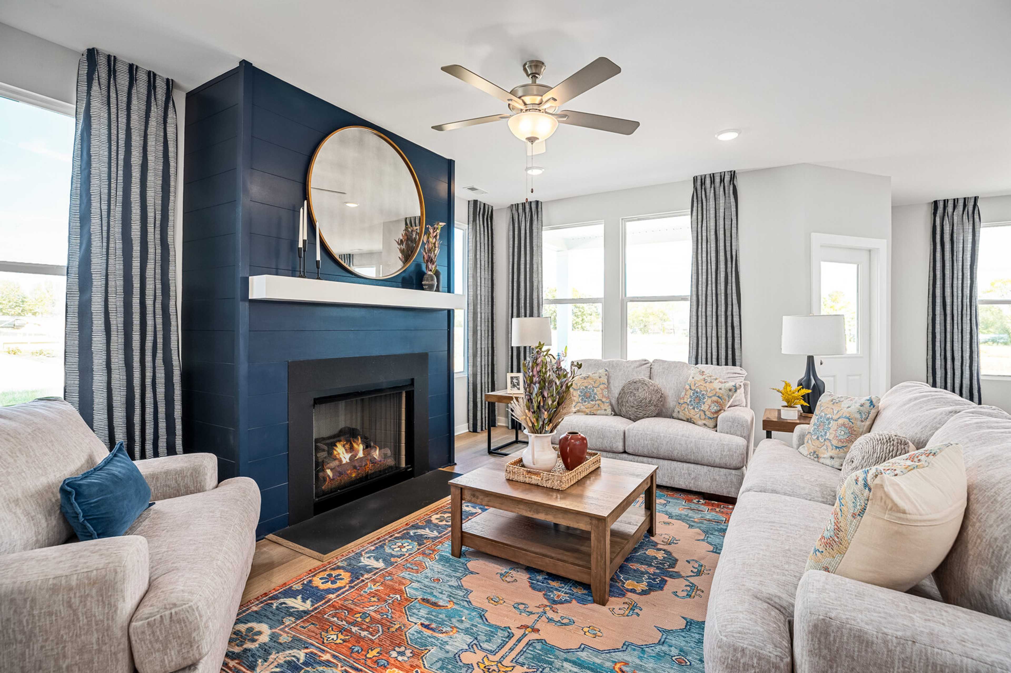 Cozy living room at Sage Farms in White House TN with navy blue fireplace, round mirror, plush sofas and patterned rug