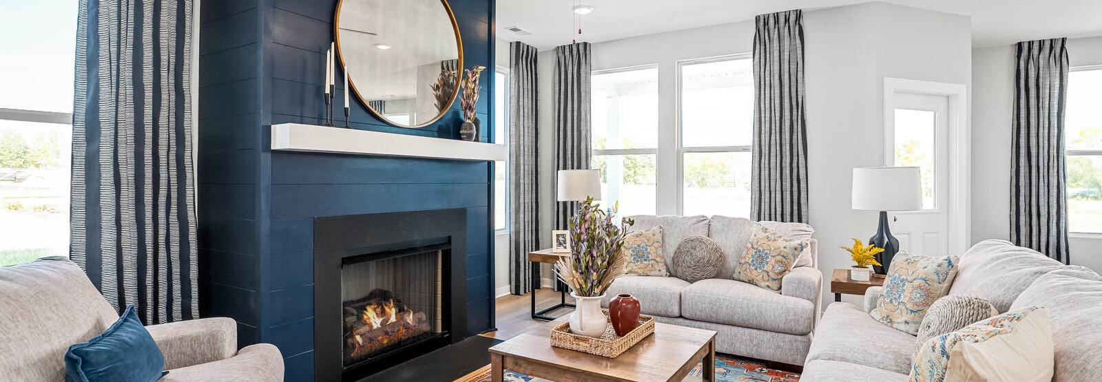 Cozy living room at Sage Farms in White House TN with navy blue fireplace, round mirror, plush sofas and patterned rug