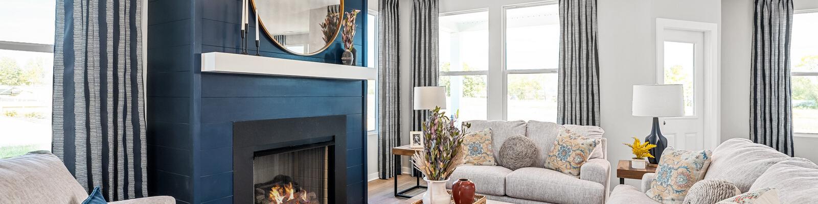 Cozy living room at Sage Farms in White House TN with navy blue fireplace, round mirror, plush sofas and patterned rug